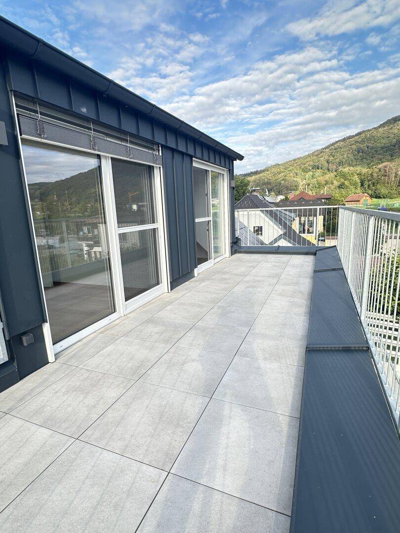 Geräumige Dachterrasse mit Fliesenboden, Metallgeländer und weitem Blick auf die umliegende Berglandschaft.