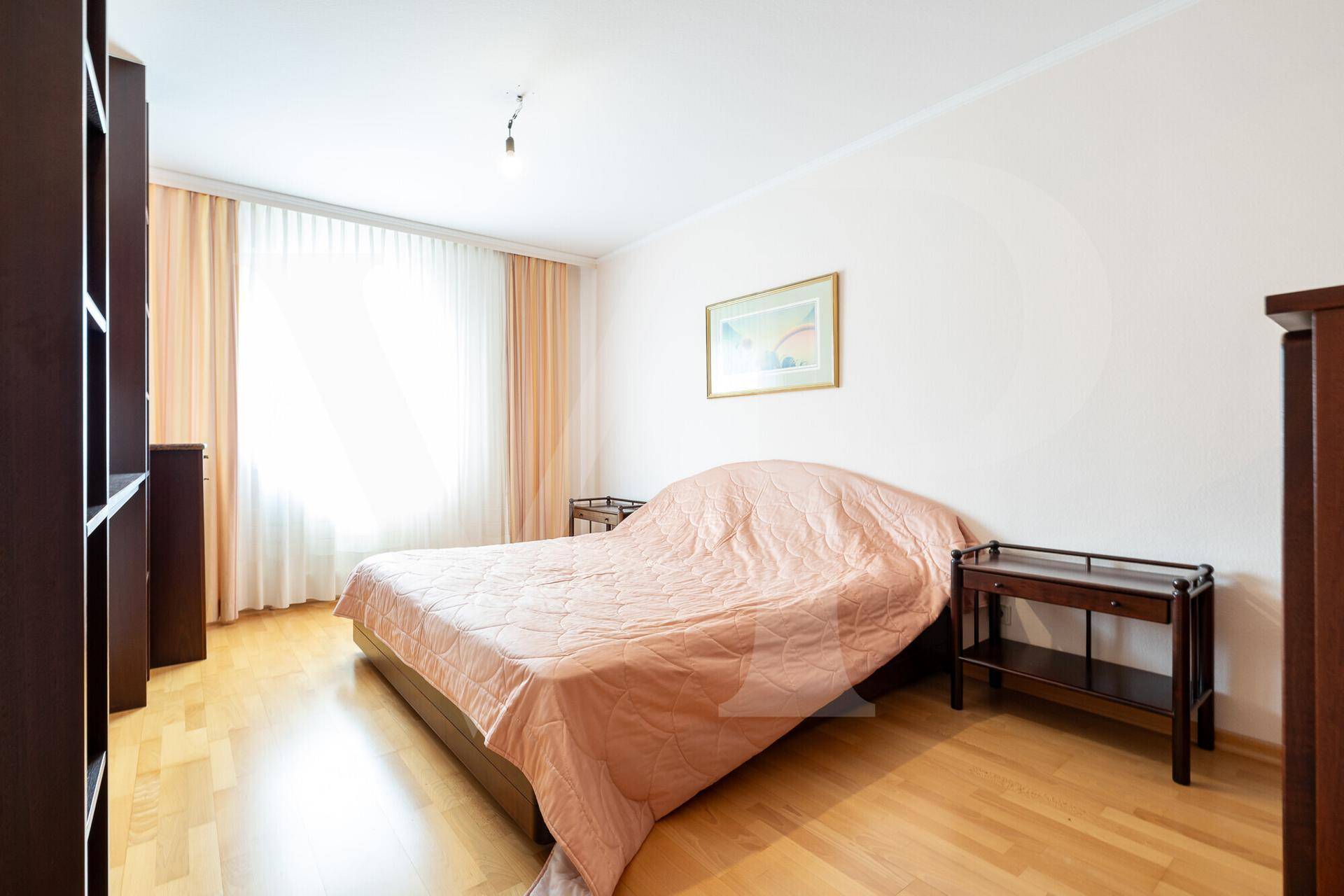 Helles Schlafzimmer mit Doppelbett, Nachttischen und Parkettboden, bietet eine ruhige Atmosphäre.