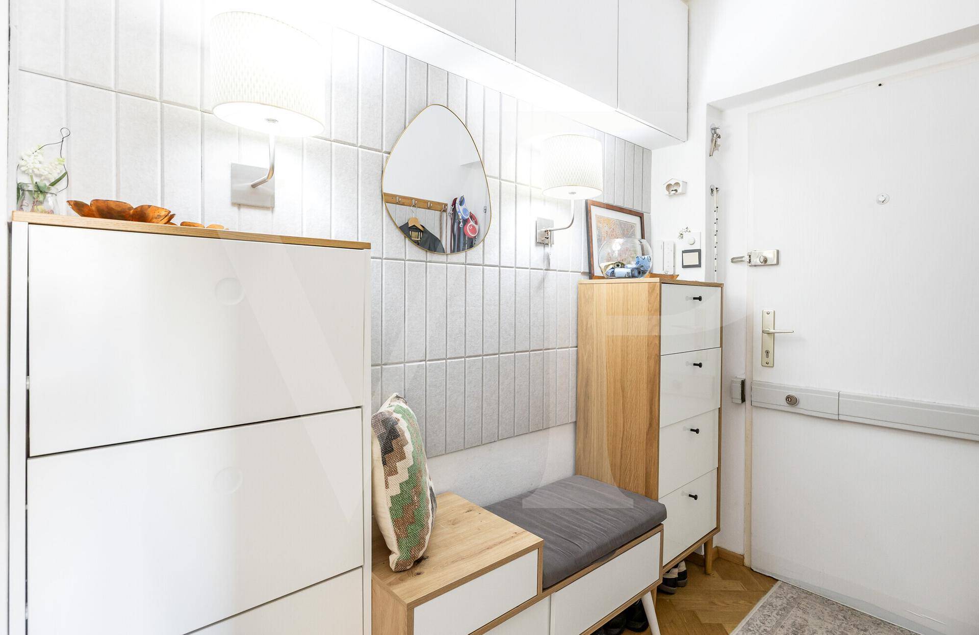 Heller Eingangsbereich mit Schuhschränken, Spiegel und Garderobe, funktional und einladend.
