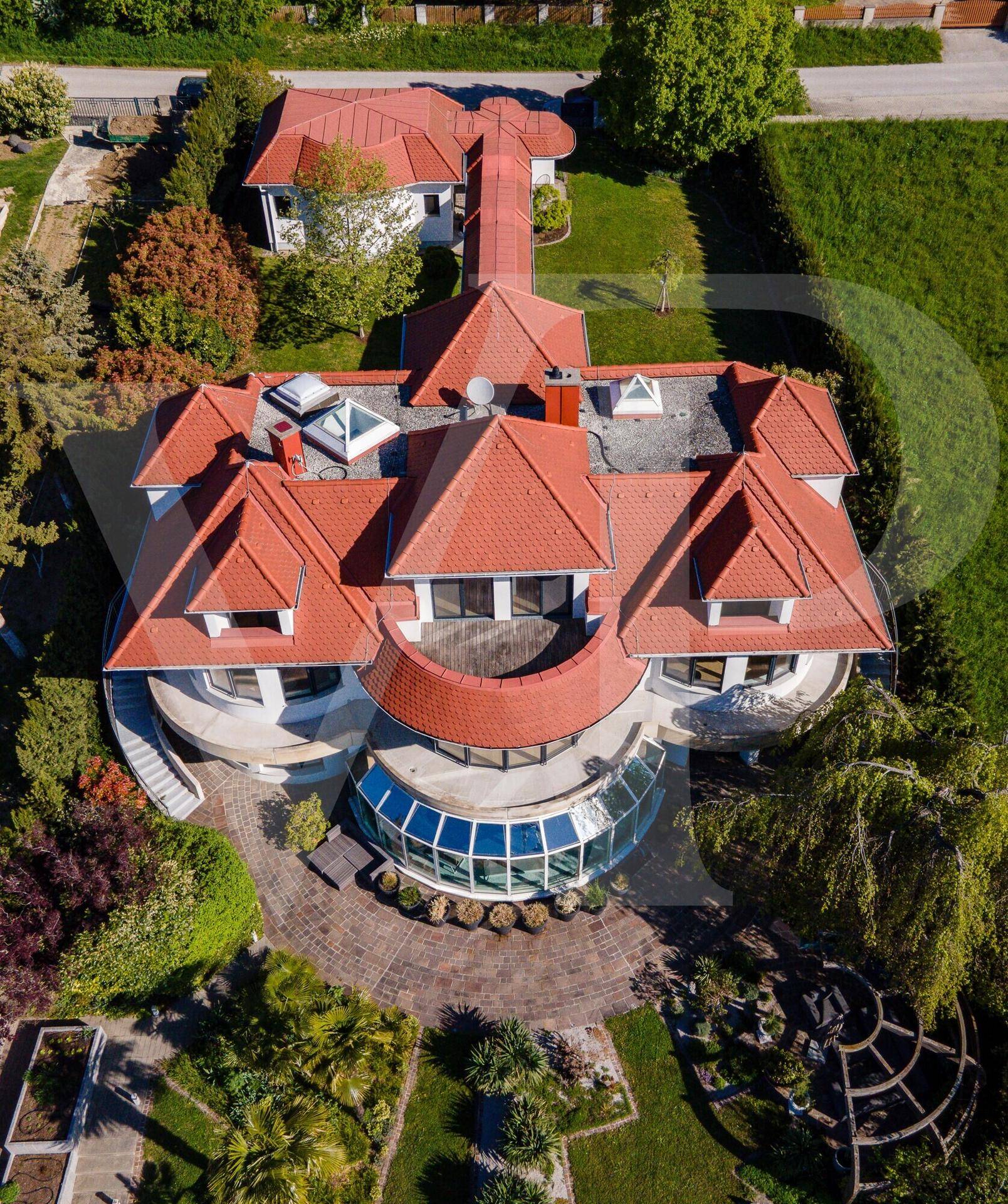 Luftaufnahme der weitläufigen Villa mit rotem Ziegeldach und großem Grundstück in grüner Umgebung.