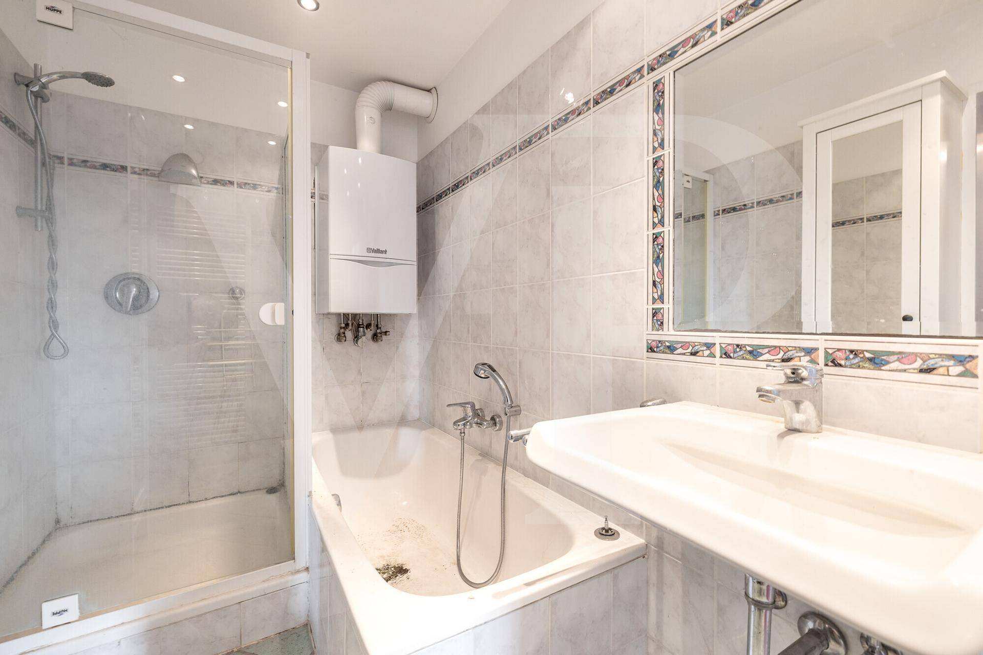 Funktionales Badezimmer mit Badewanne, Duschkabine, Waschbecken und Wandfliesen in hellen Tönen.