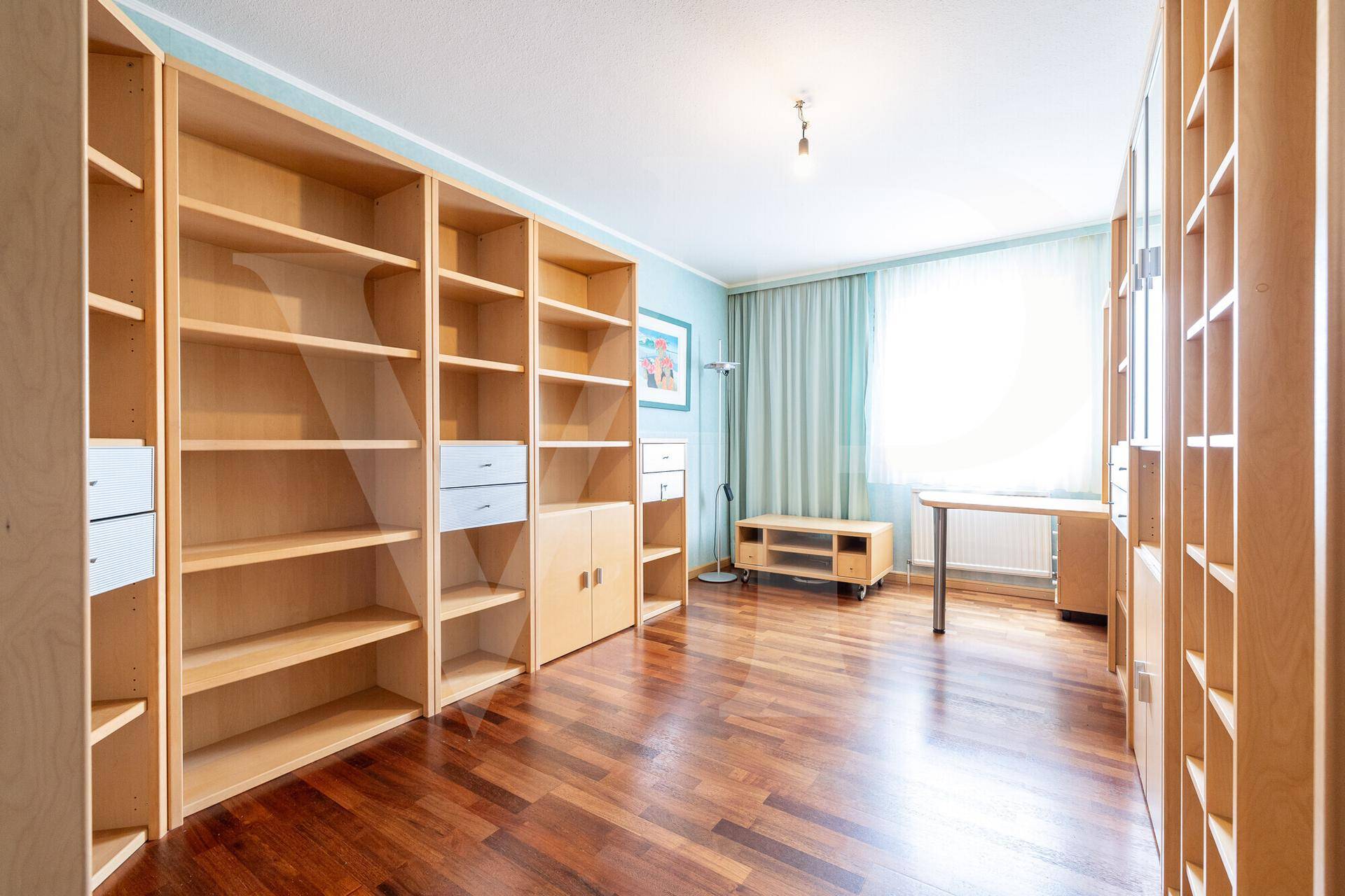Geräumiges Arbeitszimmer mit vielen Holzregalen und hellem Parkettboden, ideal für Home-Office.