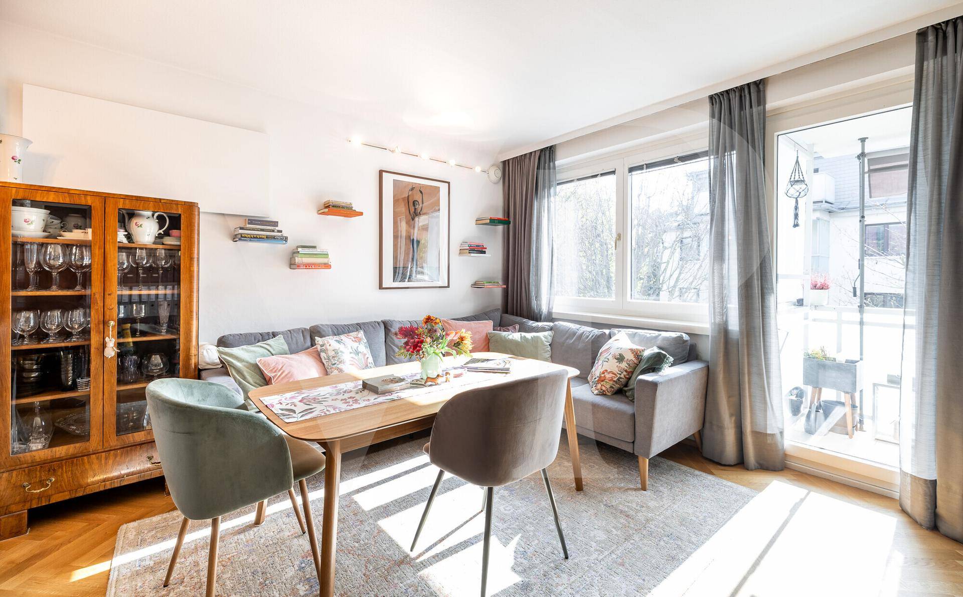 Gemütlicher Wohnbereich mit Sofa, Esstisch und Zugang zu einem sonnigen Balkon.