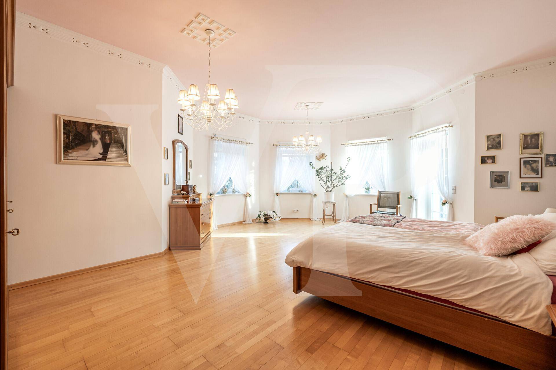 Helles und geräumiges Schlafzimmer mit Parkettboden und vielen Fenstern.