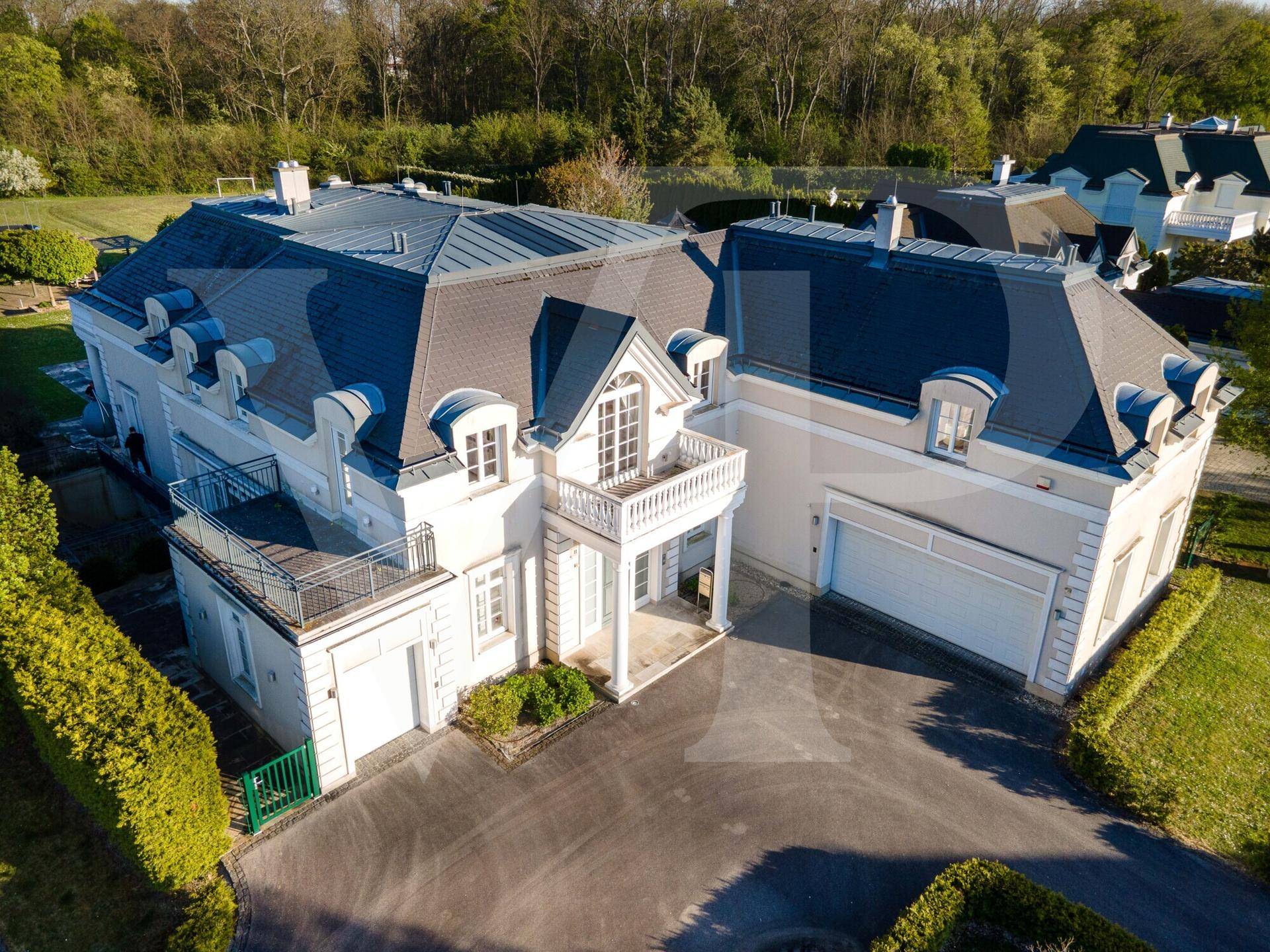 Vogelperspektive der imposanten Villa mit weitläufigem Grundstück und Garagenzufahrt.
