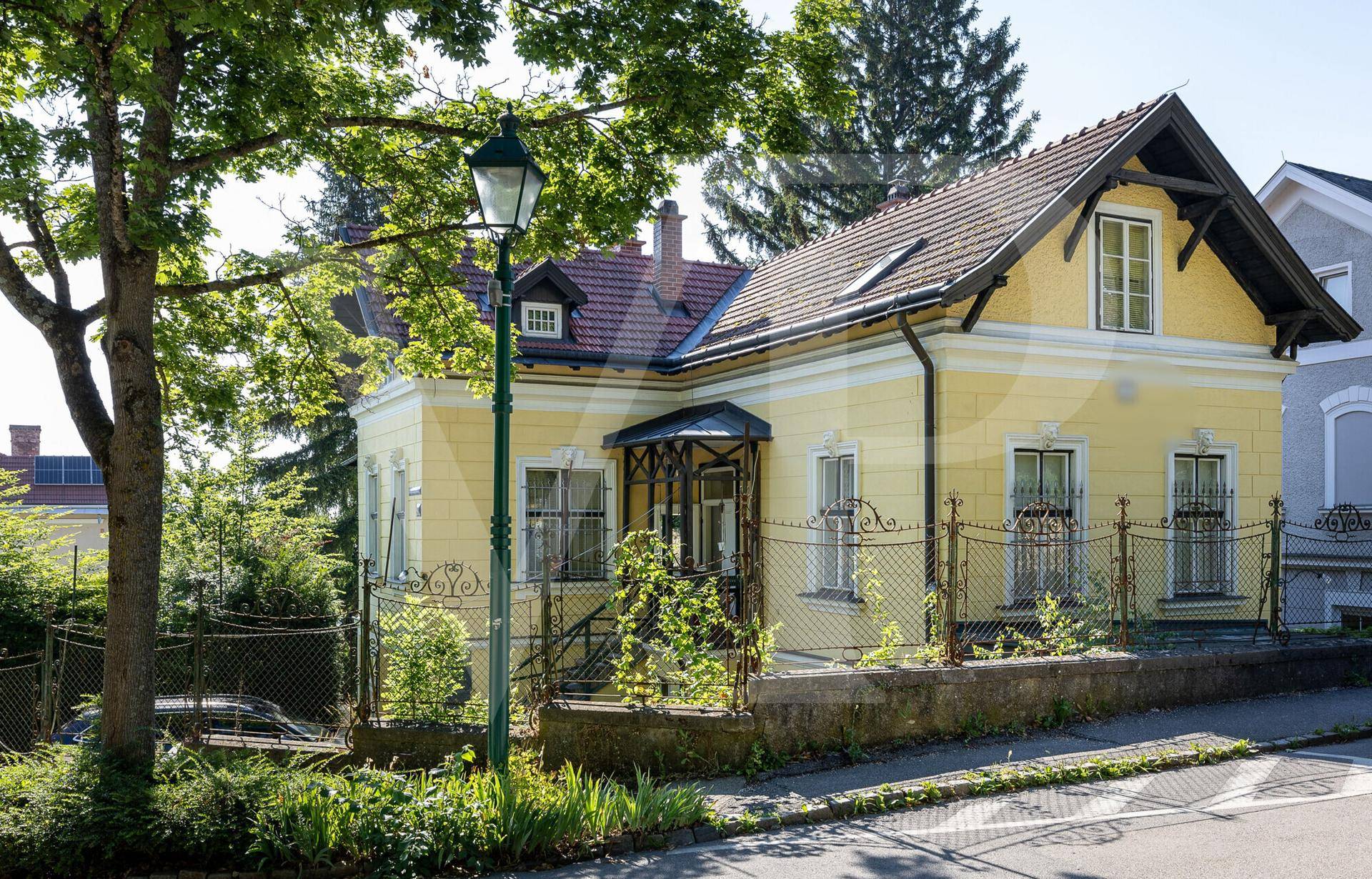 Charmantes historisches Haus mit gelber Fassade und traditionellem Eingangsbereich an einer Straße.
