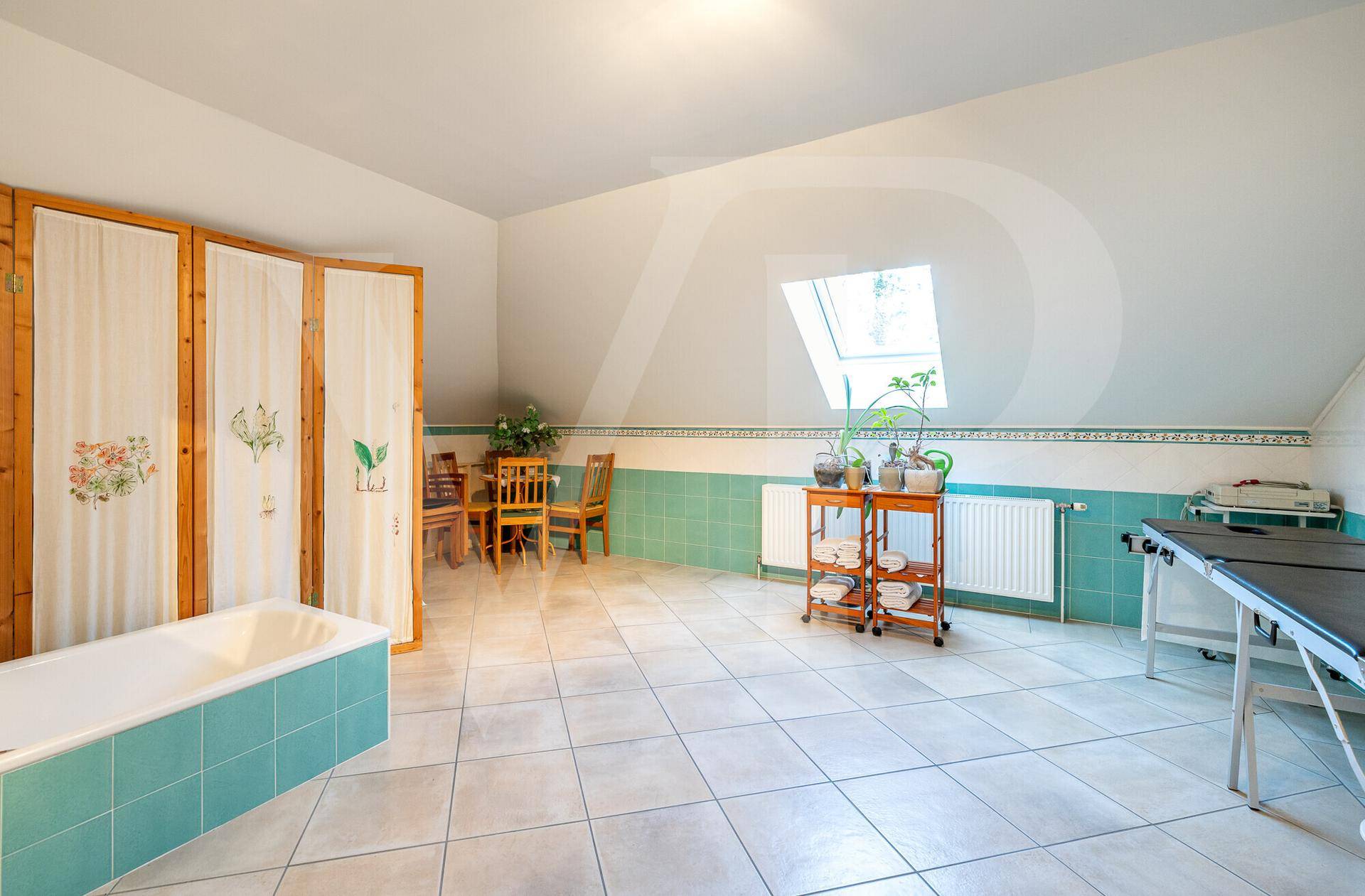 Heller Dachbodenraum mit Badewanne, Fliesenboden und Dachfenster.