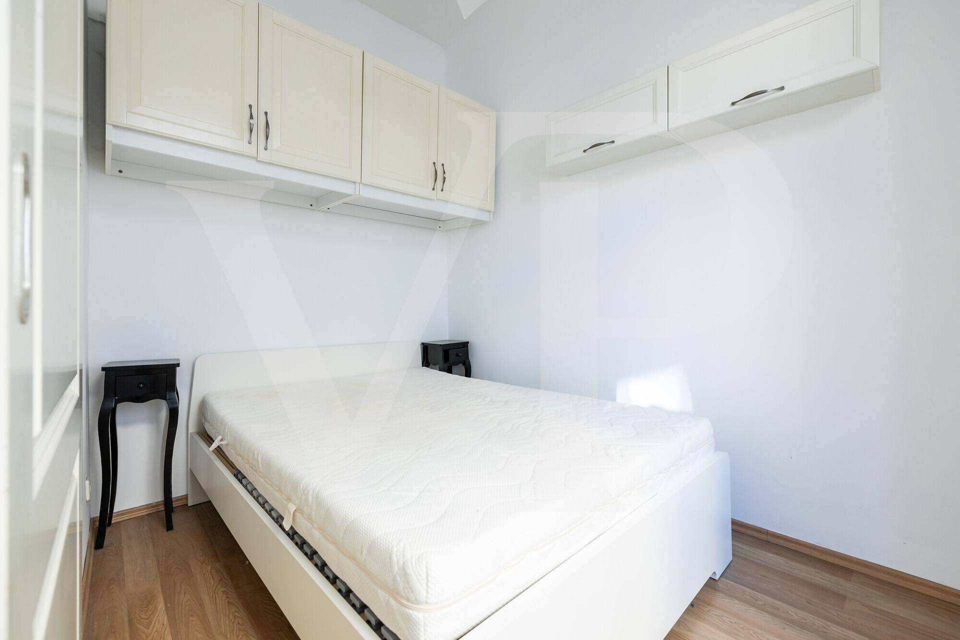 Gemütliches Schlafzimmer mit Holzboden, Nachttischen und Hängeschränken.