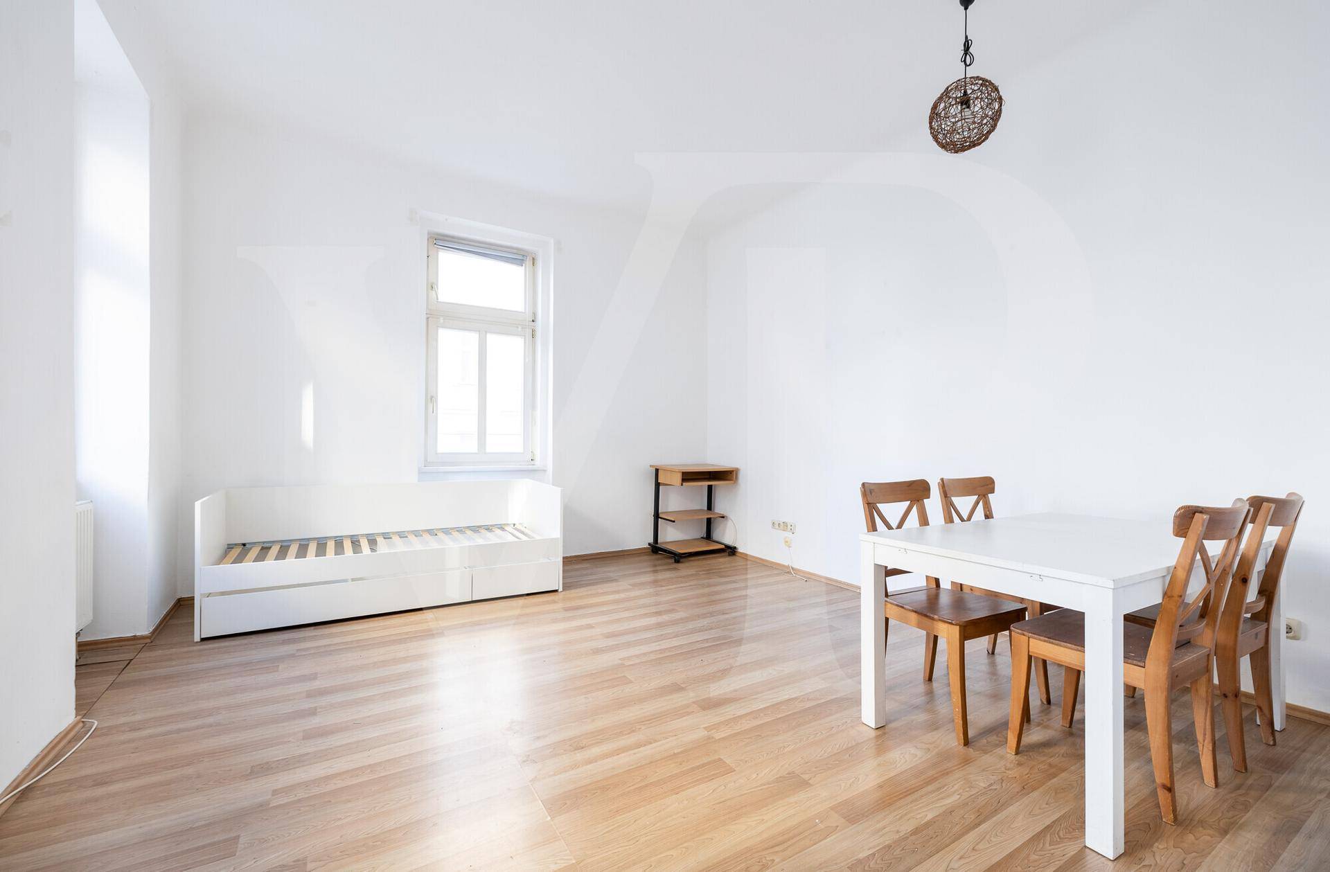 Heller Wohnbereich mit Holzboden, Tagesbett und Esstisch, ideal für flexible Nutzung.