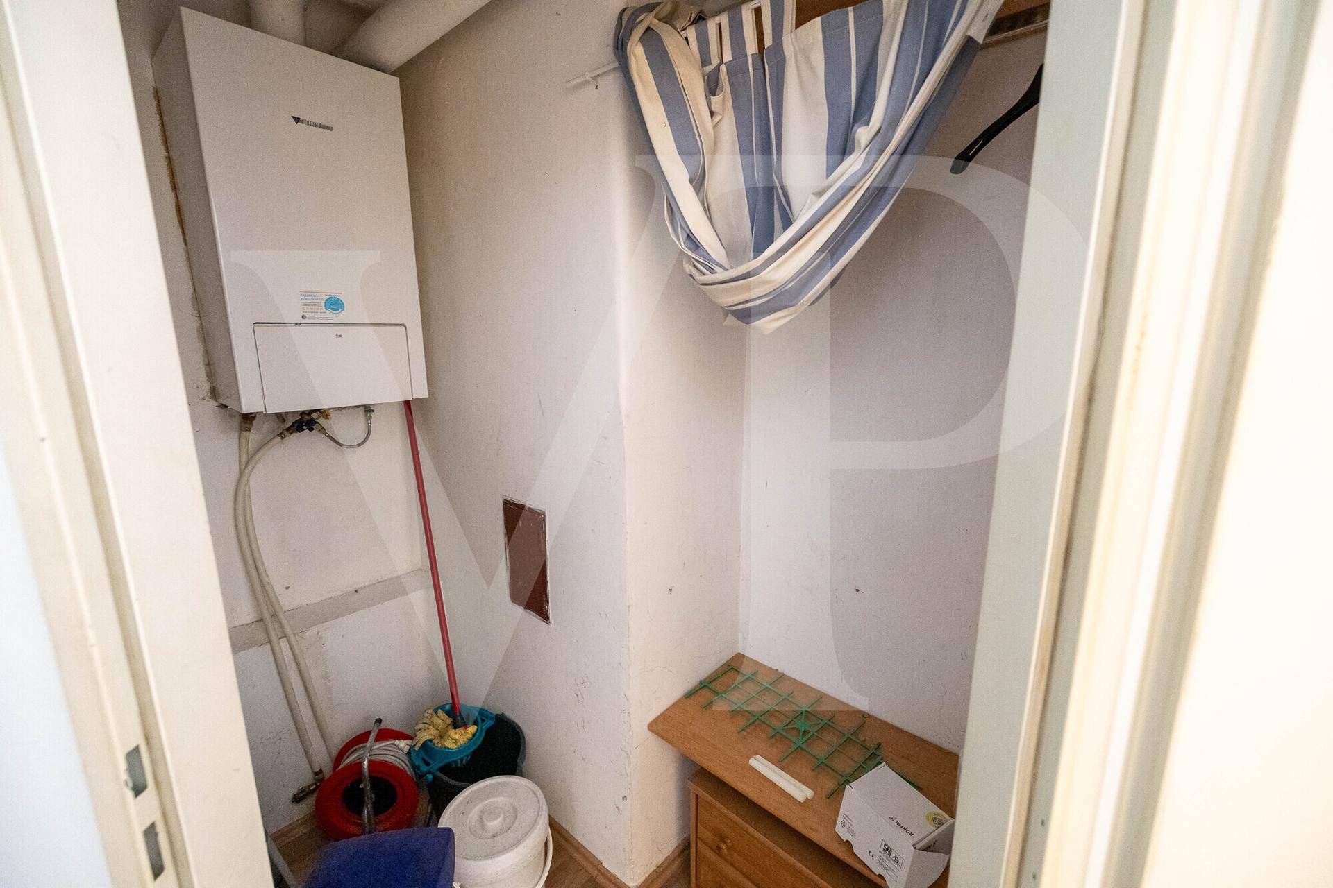 Kleiner Abstellraum mit Heizungsanlage und Stauraum für Haushaltsgegenstände.