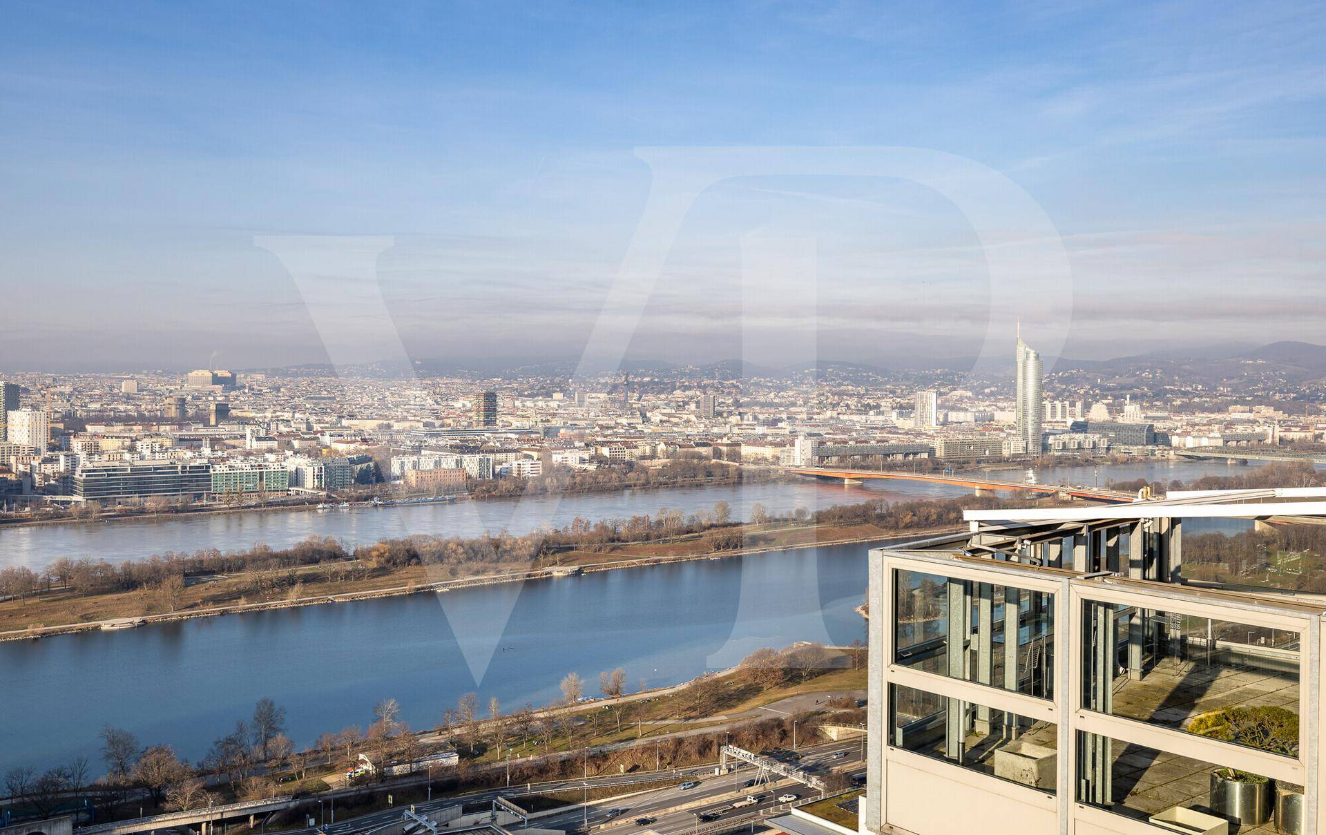 Blick über die Stadt und den Fluss, mit einem modernen Gebäude im Vordergrund und weiter Skyline.