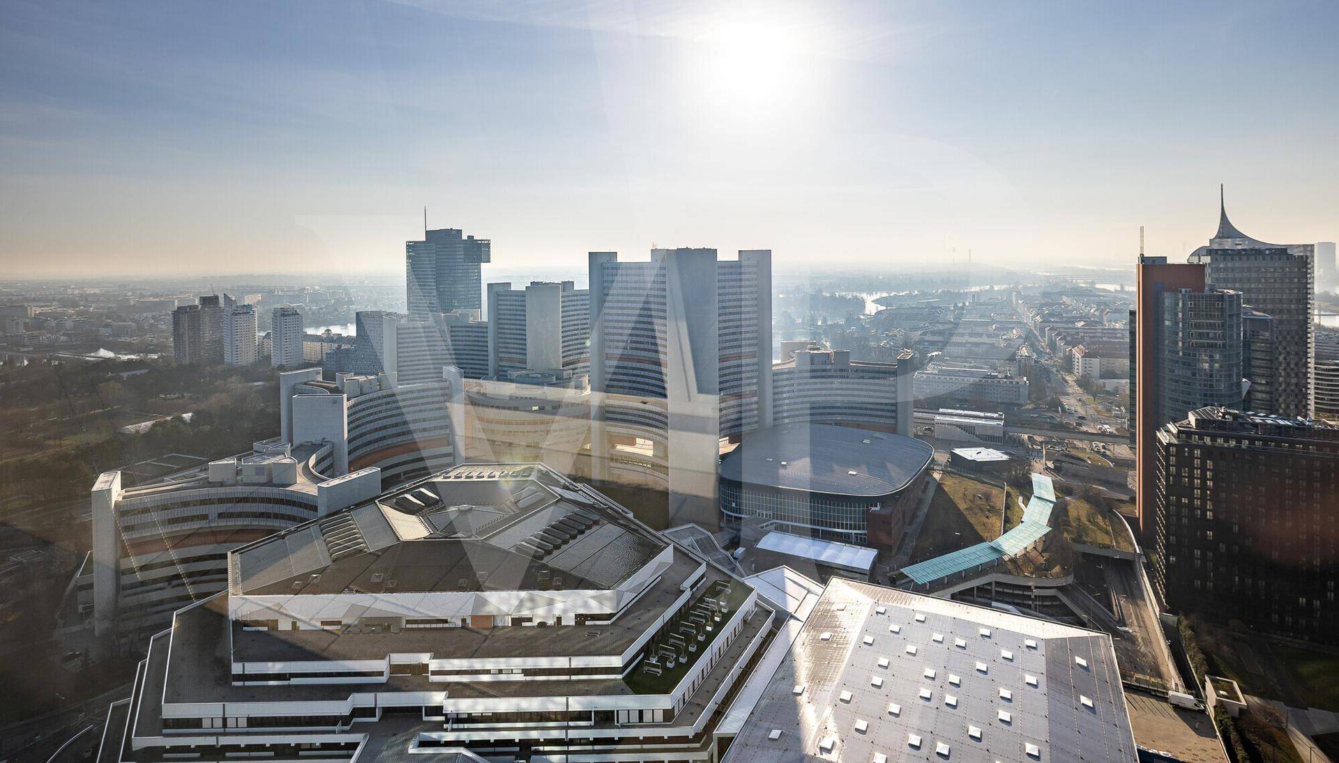 Architektonischer Blick auf moderne Gebäude mit markanten Formen und Sonnenreflexionen.