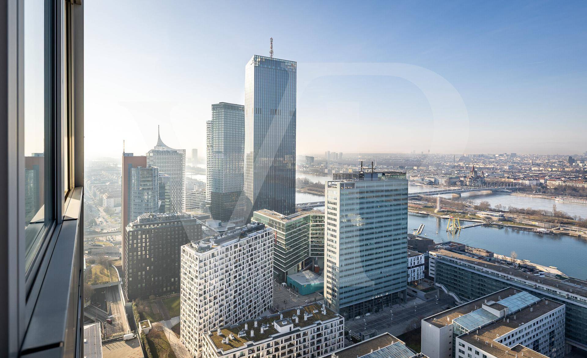 Blick aus einem Fenster auf die moderne Stadtlandschaft mit Hochhäusern und dem Fluss.