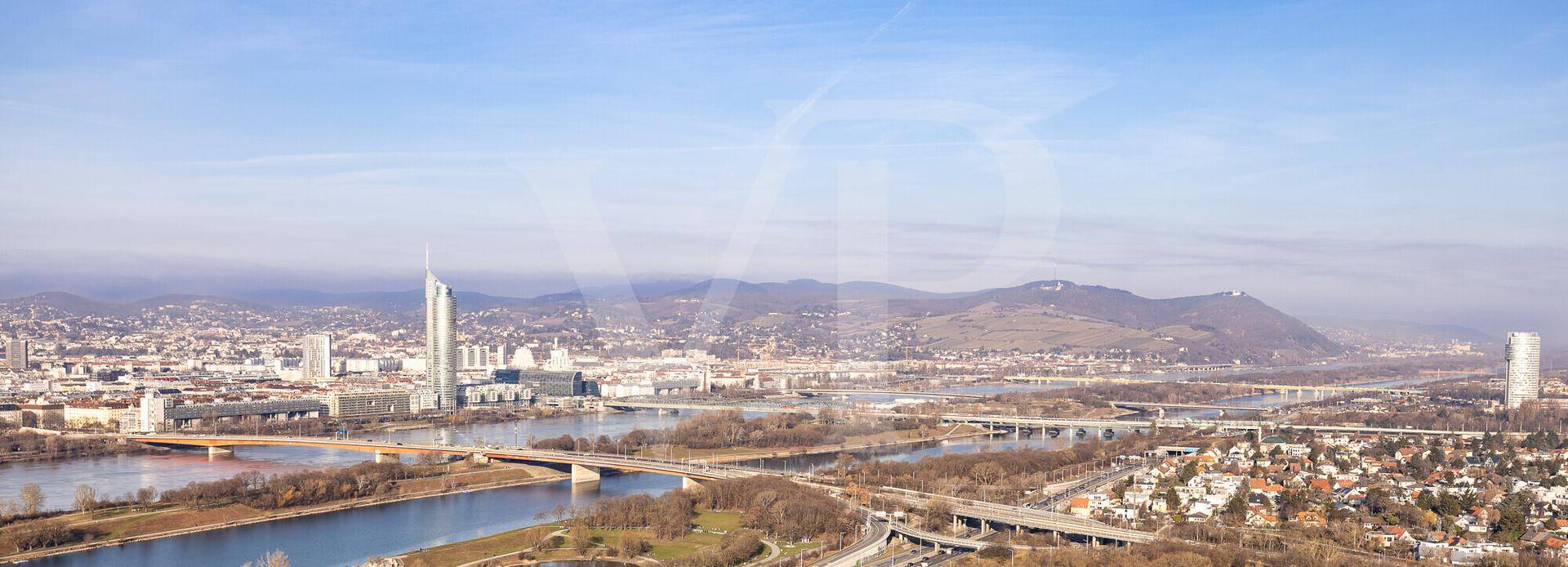 Panoramablick über die Stadt mit Fluss, Brücken und den umliegenden Bergen am Horizont.