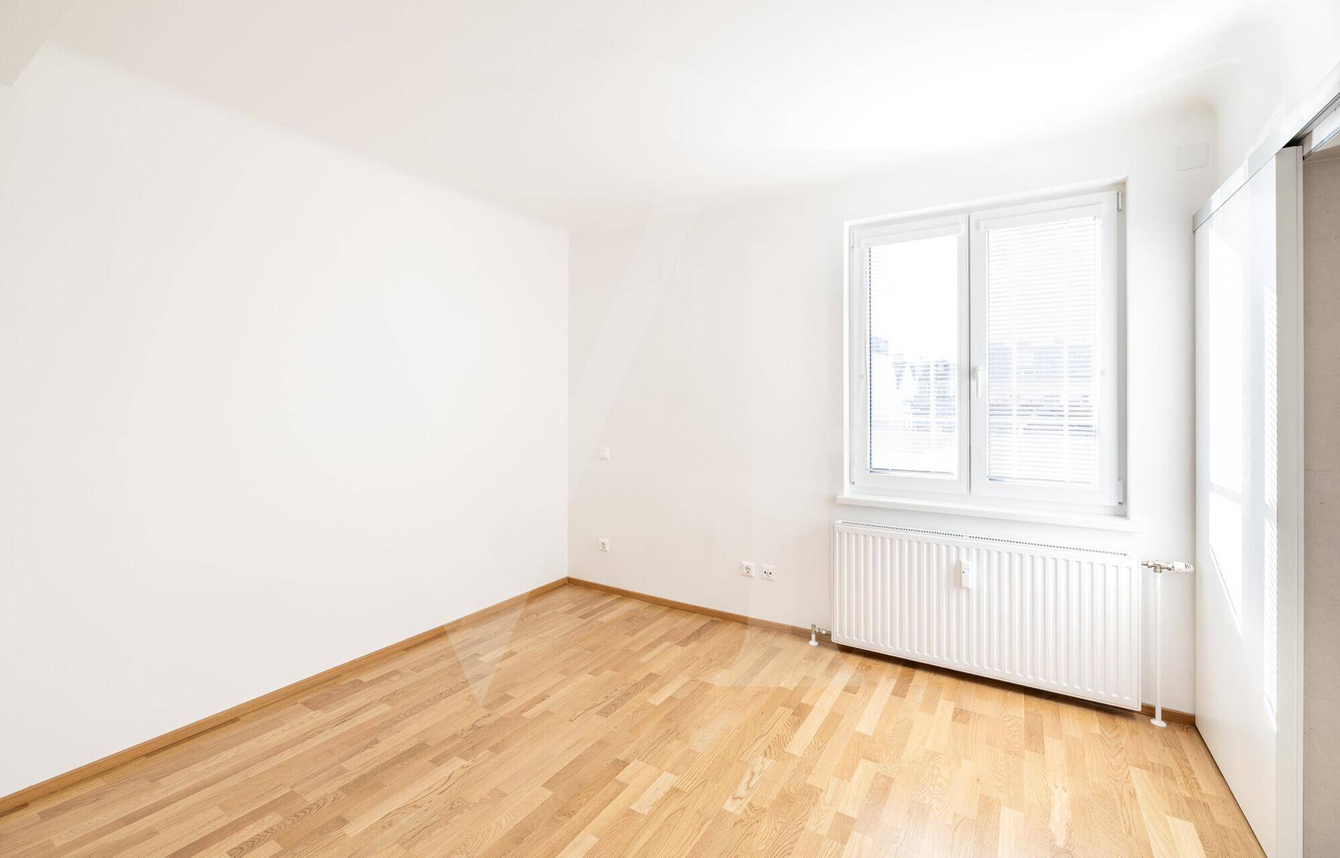Helles Schlafzimmer mit Parkettboden und großem Fenster, bereit zur individuellen Gestaltung.