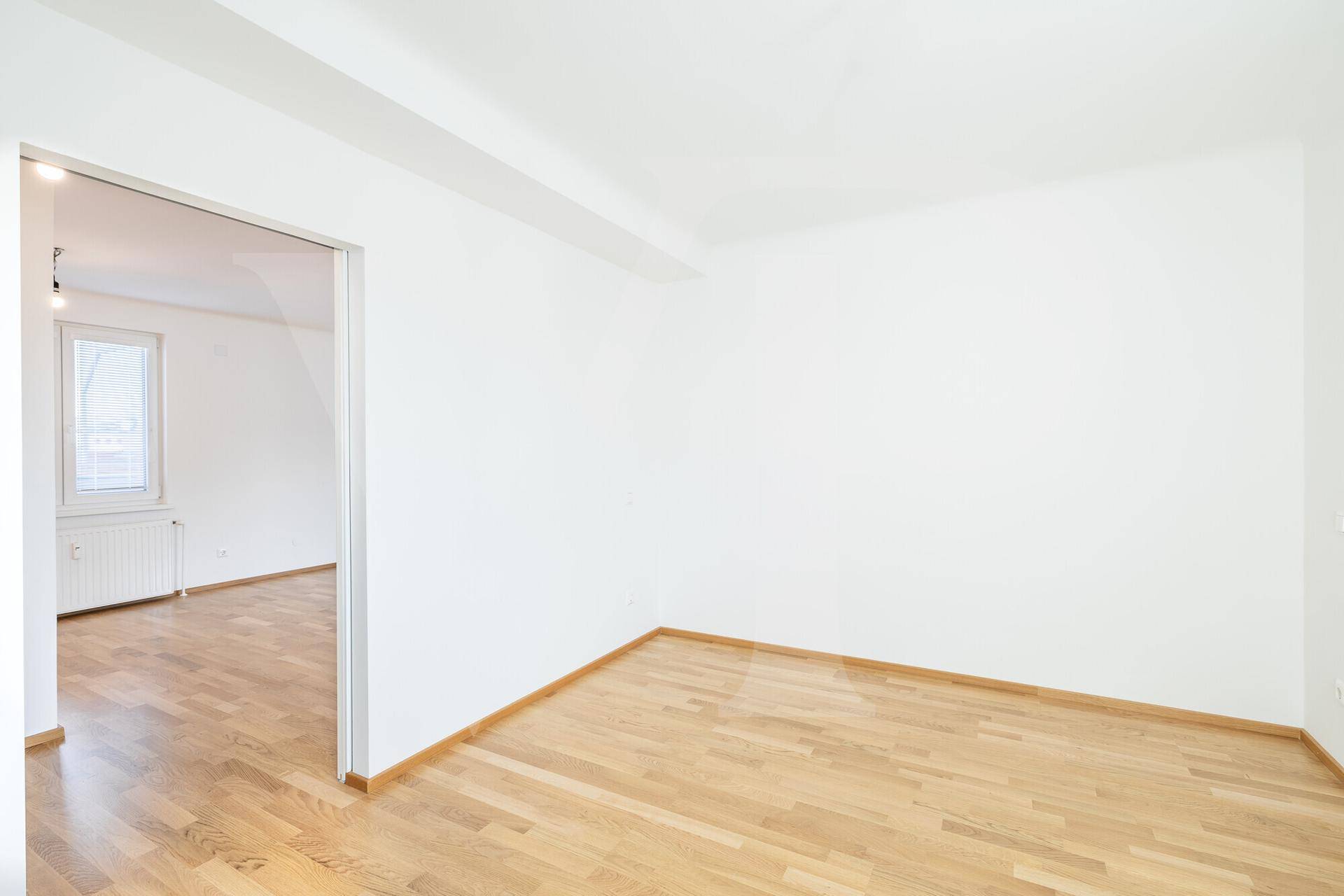 Leeres Schlafzimmer mit Parkettboden und weiß gestrichenen Wänden, ideal für neue Einrichtung.