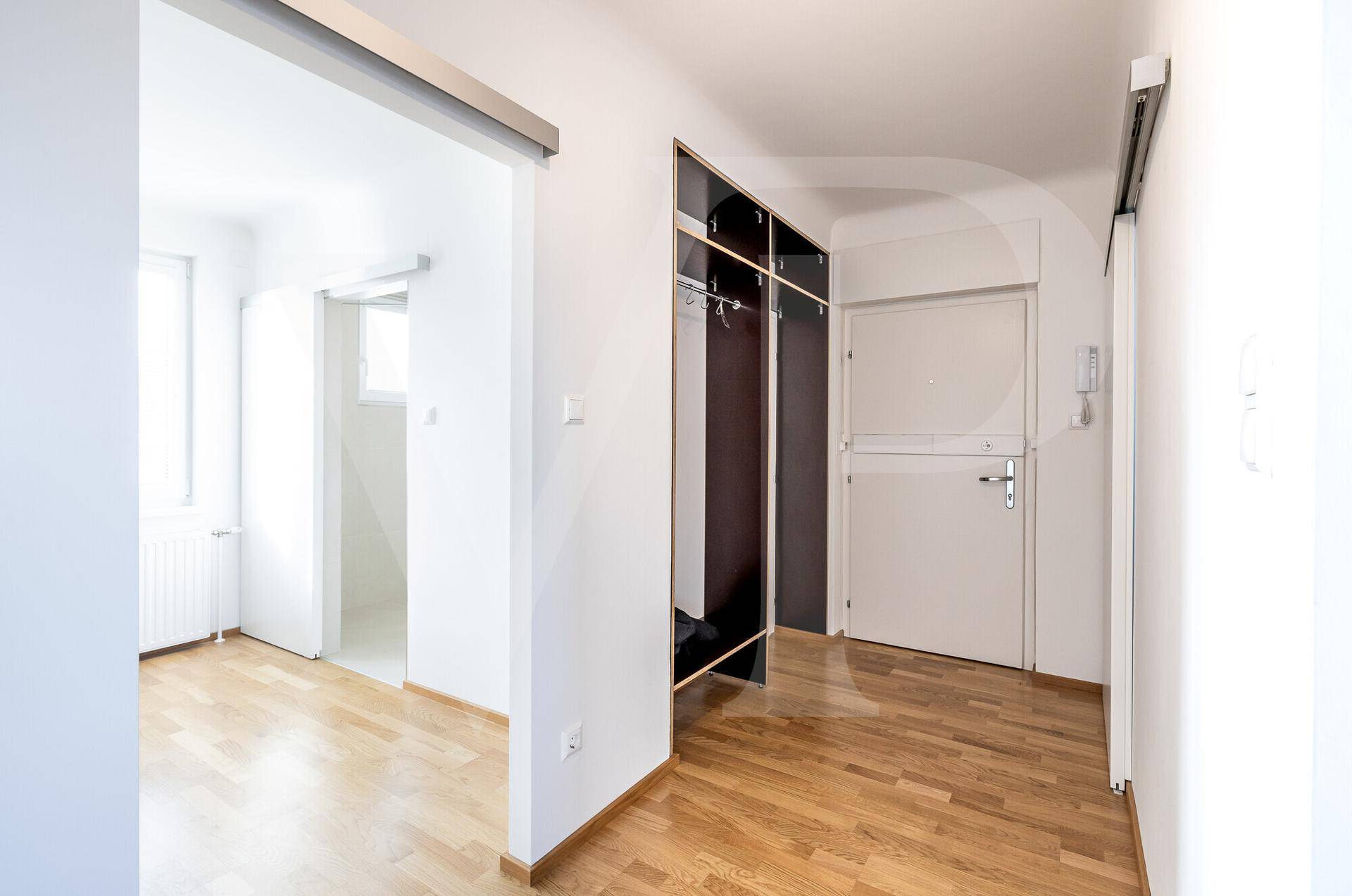 Heller Flur mit Parkettboden und integriertem Garderobenschrank, der zu den Zimmern führt.