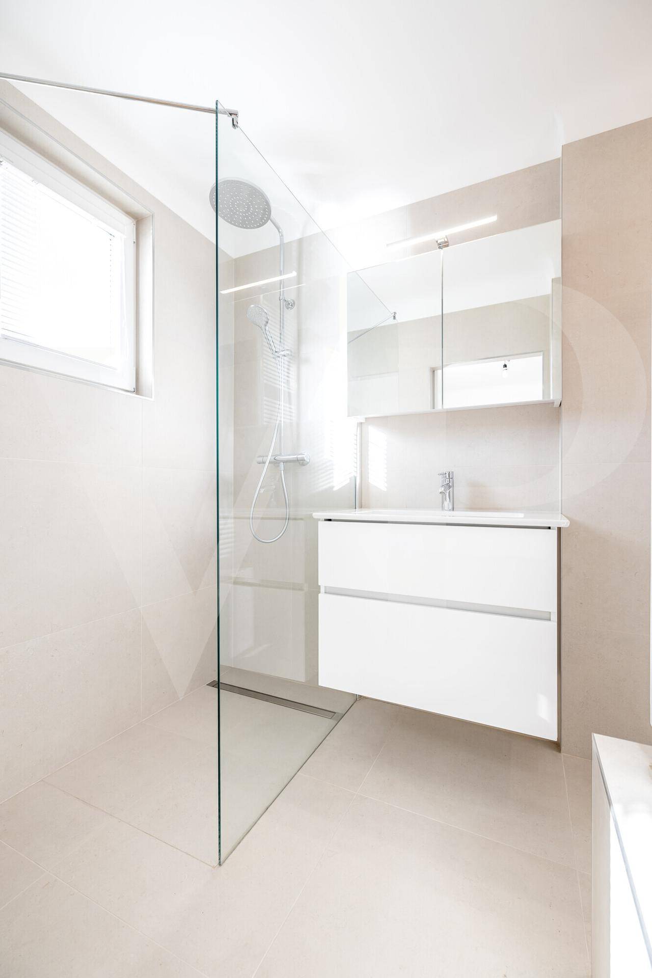 Modernes Badezimmer mit begehbarer Dusche, Waschtisch und Fenster für Tageslicht.