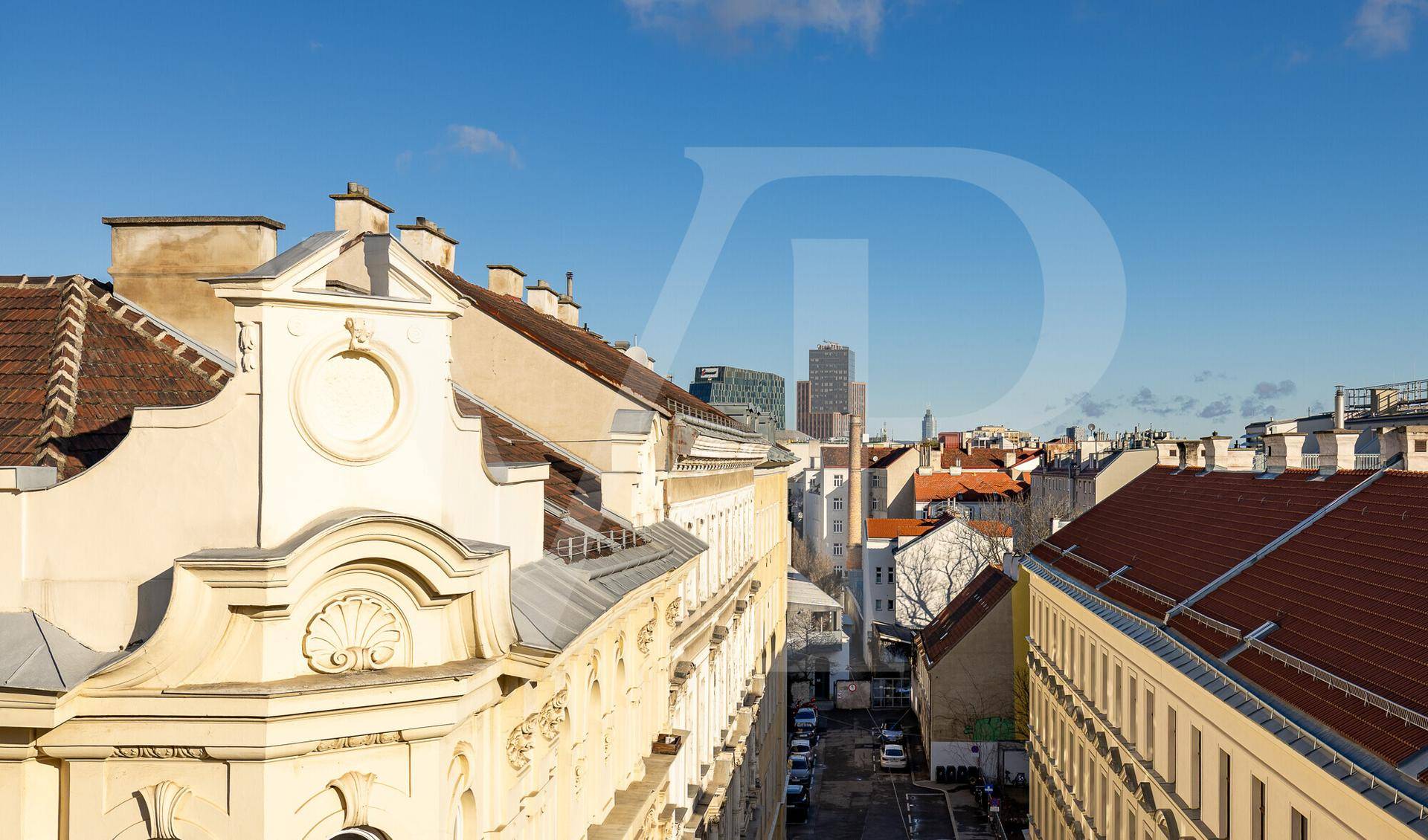 Panoramablick über die Dächer der Stadt mit historischer Architektur und modernen Gebäuden im Hintergrund.