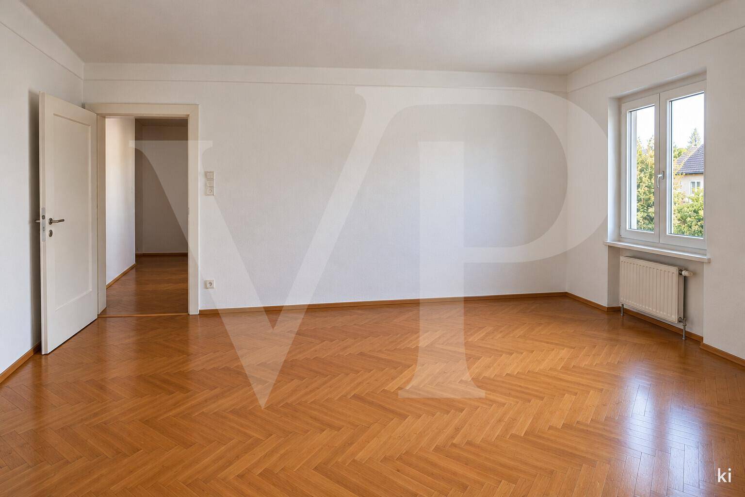 Geräumiges Zimmer mit glänzendem Fischgrätparkett und frisch gestrichenen weißen Wänden.
