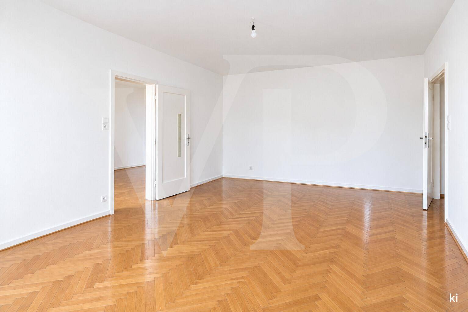 Wohnzimmer mit auffälligen rosa Wänden, rotem Sofa und traditionellem Fischgrätparkettboden.