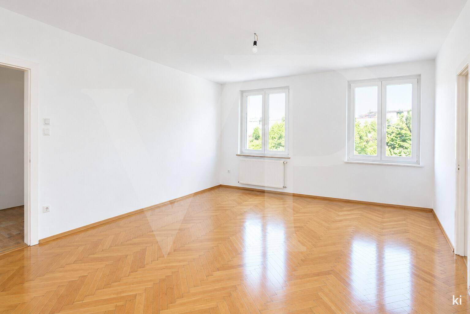 Geräumiges Wohnzimmer mit rosa Wänden, Holzmöbeln und einem bequemen roten Ecksofa.