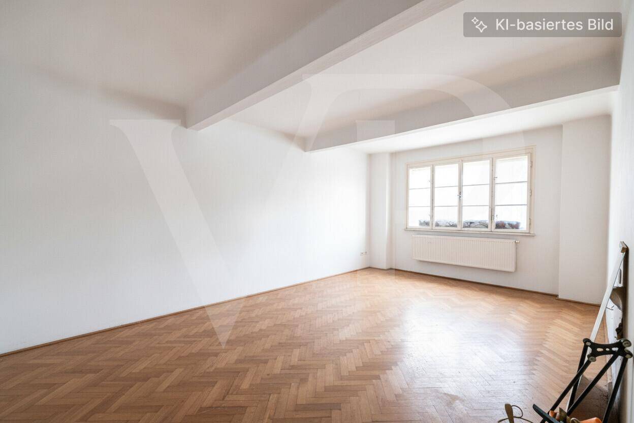 Heller Raum mit Fischgrätparkettboden, weißen Wänden und einem Deckenbalken.