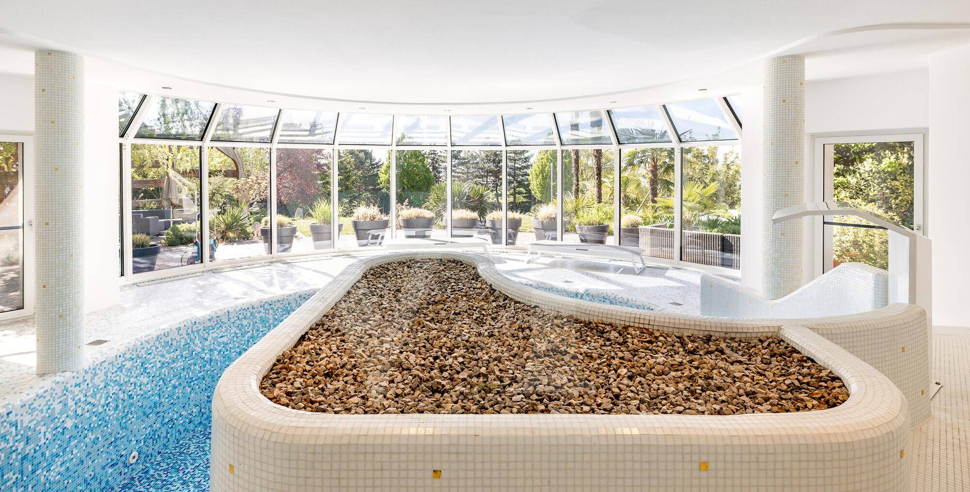 Exklusiver Wellnessbereich mit Innenpool, Whirlpool und großen Glasfronten zum Garten.