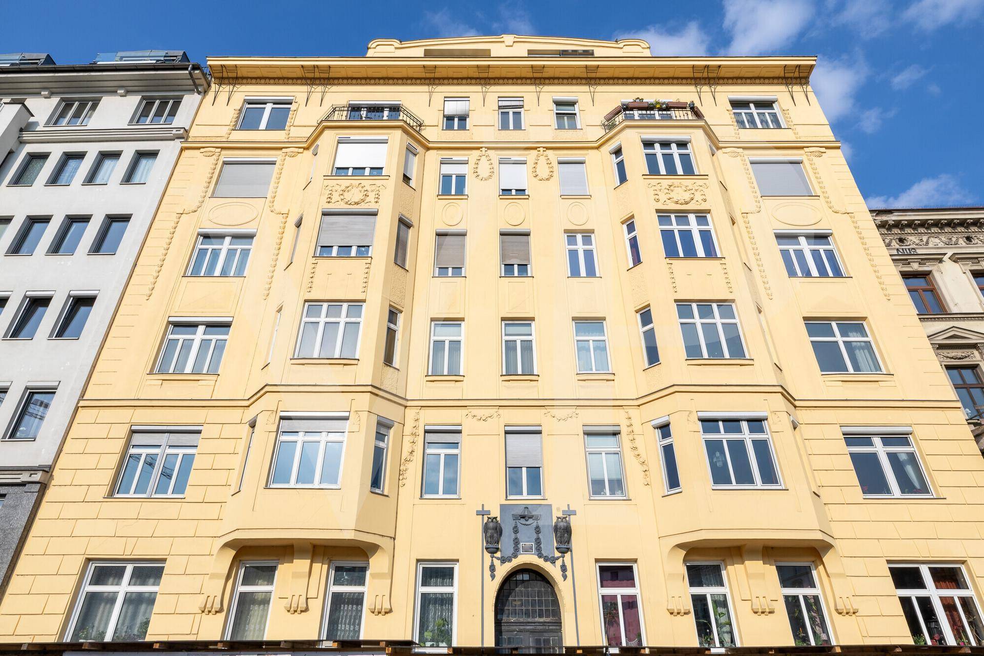 Historisches Gebäude mit gelber Fassade, vielen Fenstern und dekorativen Elementen.