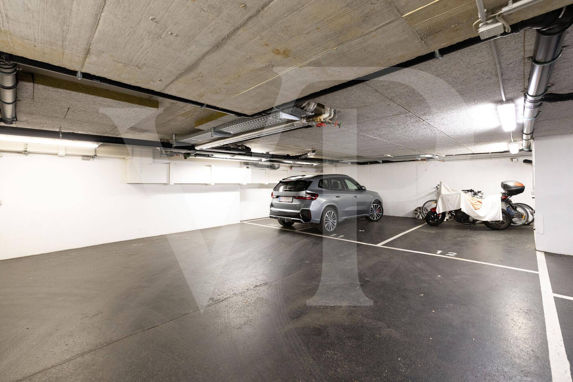 Saubere Tiefgarage mit markierten Parkplätzen, Betonstrukturen und guter Beleuchtung.