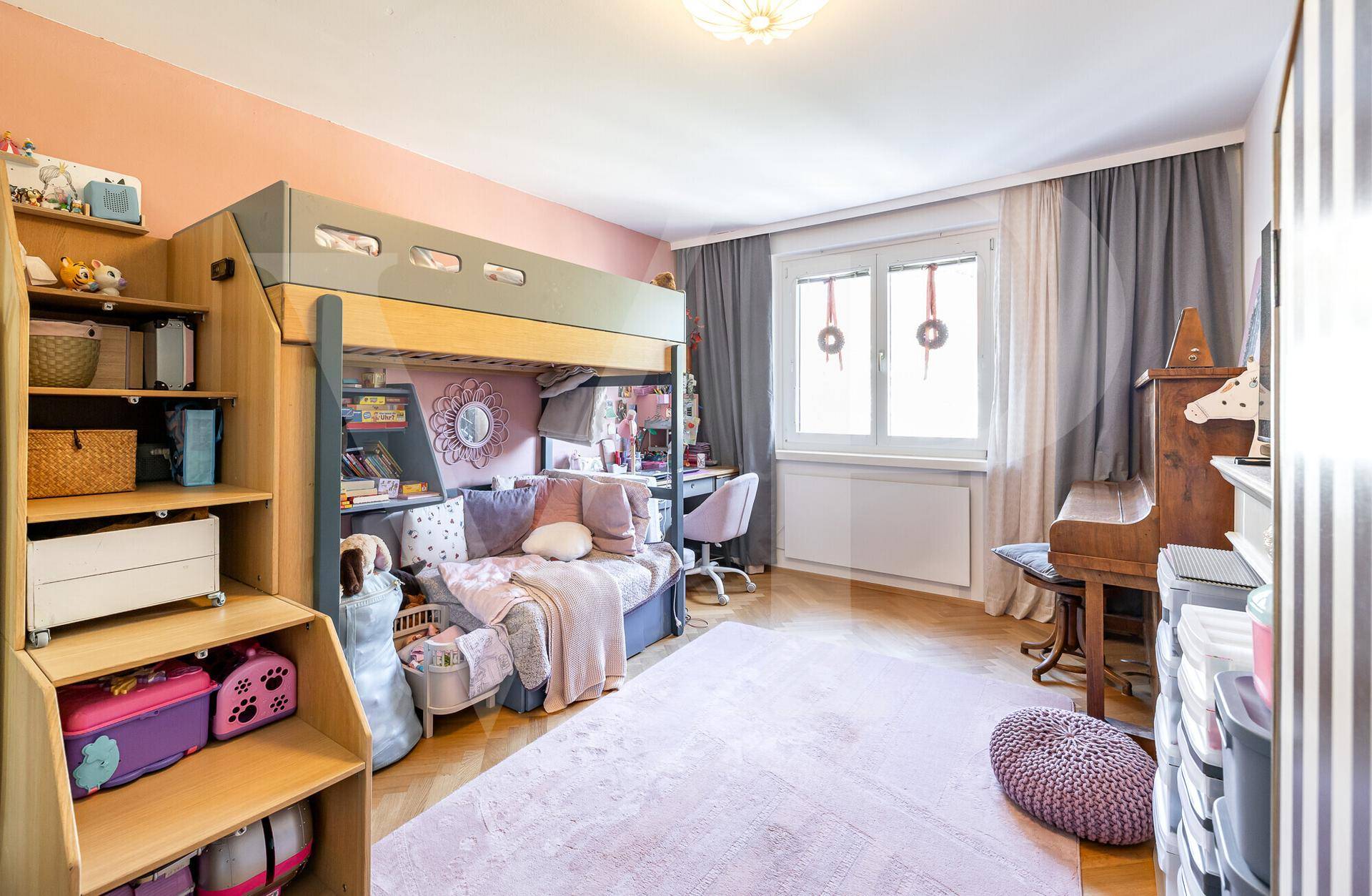 Kinderzimmer mit Hochbett, Schreibtisch und rosa Teppich, hell und freundlich gestaltet.