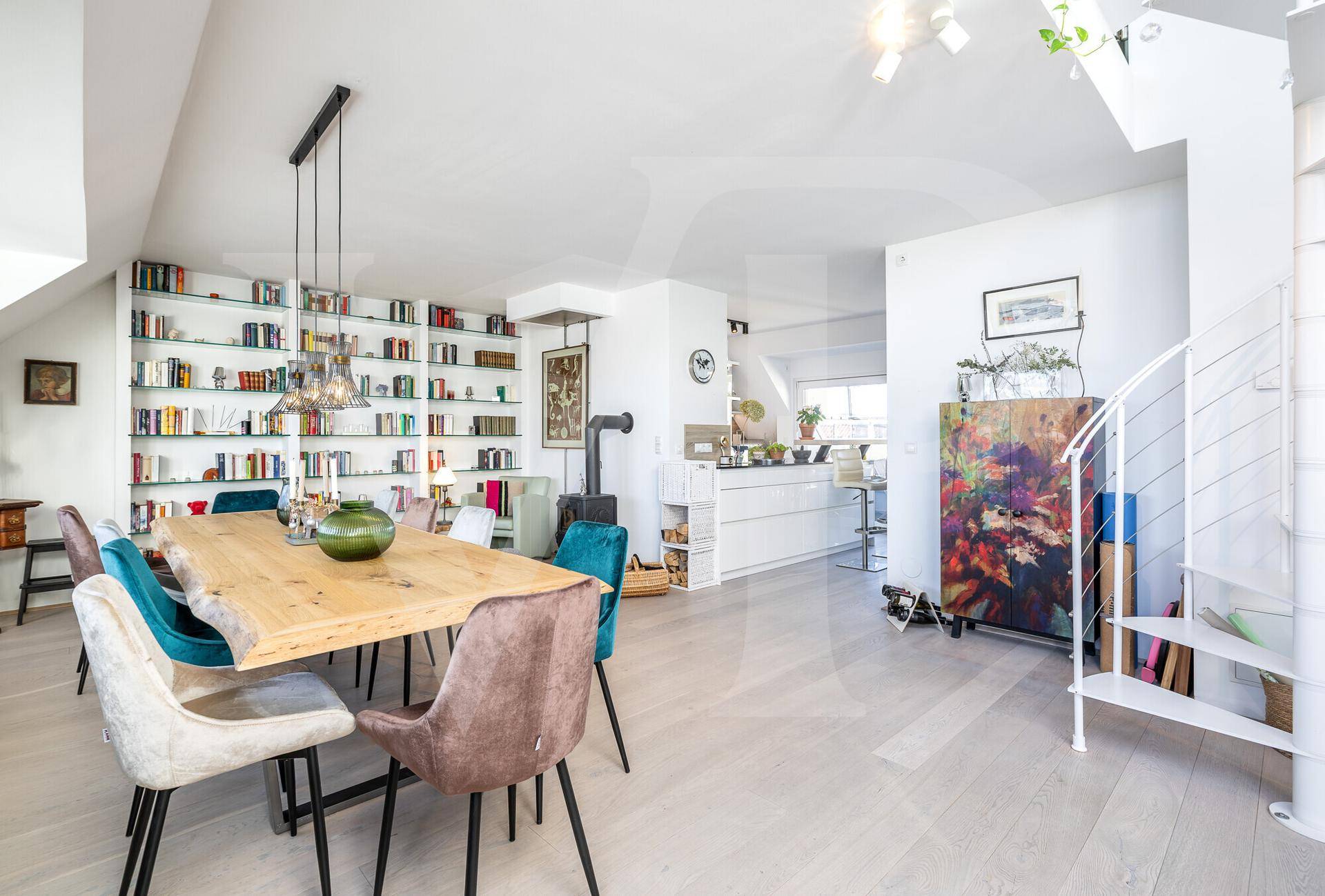 Offener Wohn-Essbereich mit Holztisch, Bücherregal und Blick zur modernen Küche.