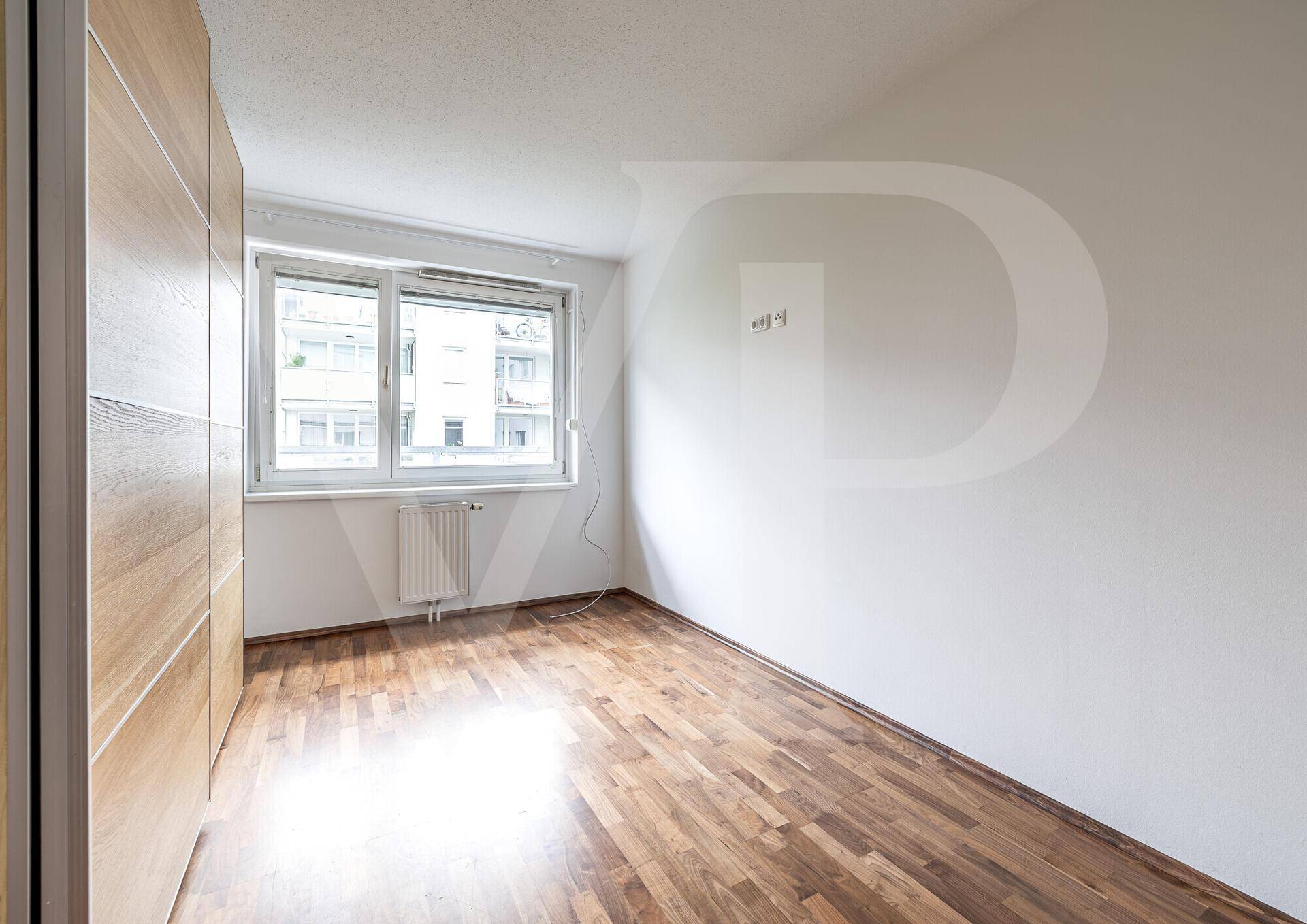 Helles Schlafzimmer mit Holzboden und großem Fenster, bietet viel Tageslicht.