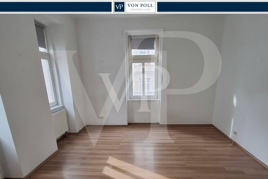 Geräumiges Zimmer mit viel Tageslicht und neuwertigem Laminatboden.