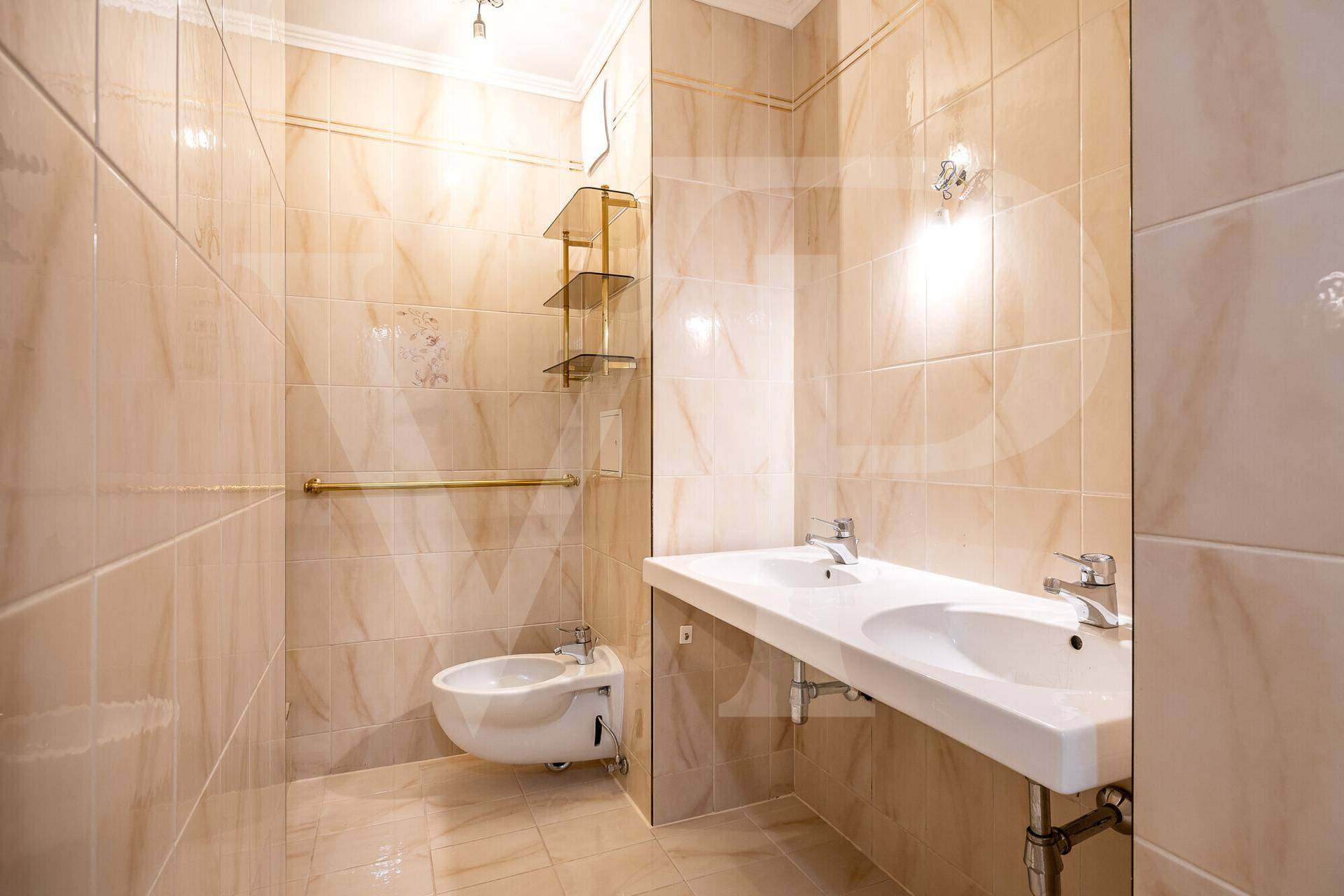 Geräumiges Badezimmer mit beigen Fliesen, Doppelwaschbecken und Bidet, in gutem Zustand.