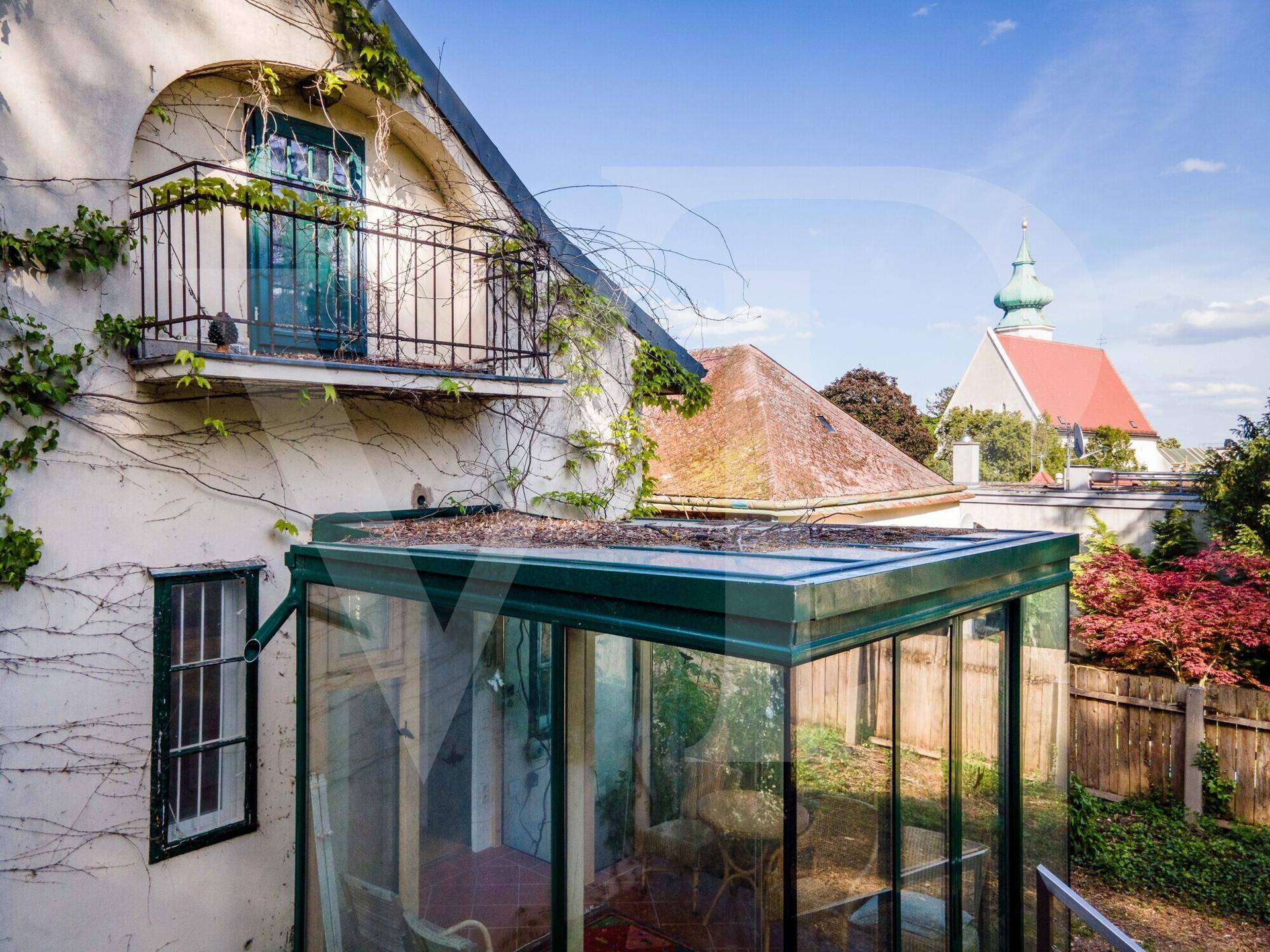 Heller Wintergarten mit Blick auf den Garten und einen französischen Balkon am historischen Haus.