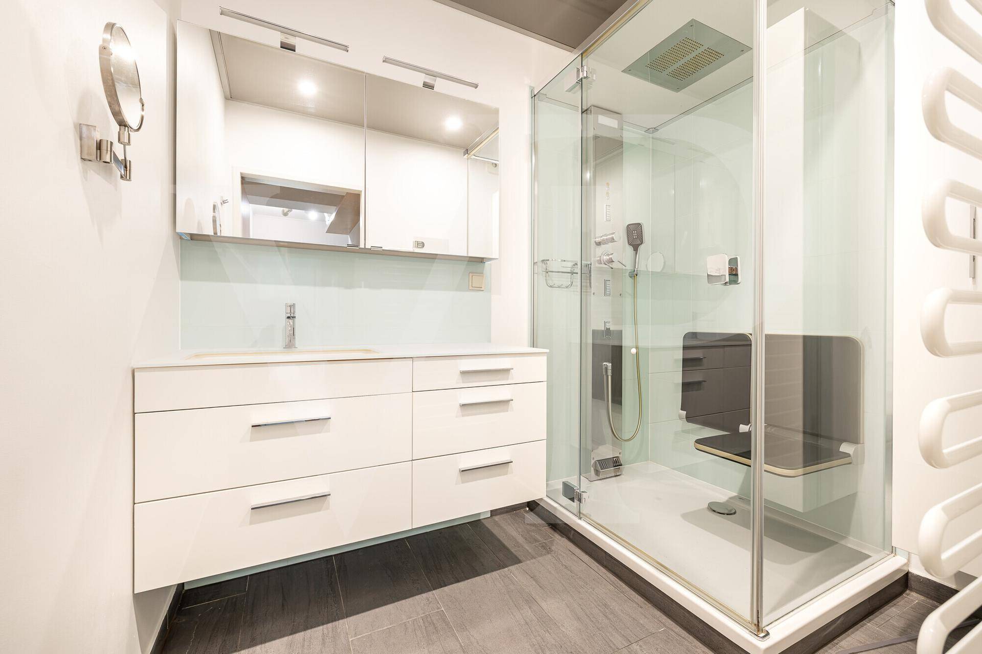 Modernes Badezimmer mit ebenerdiger Dusche, Waschtisch und beheiztem Handtuchhalter.