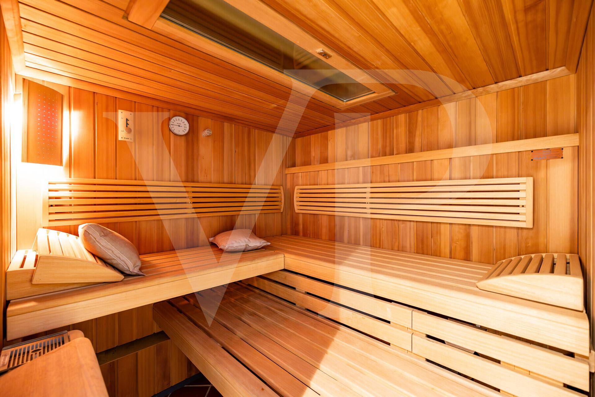Gemütliche Holzsauna mit mehreren Bänken und indirekter Beleuchtung für Entspannung.