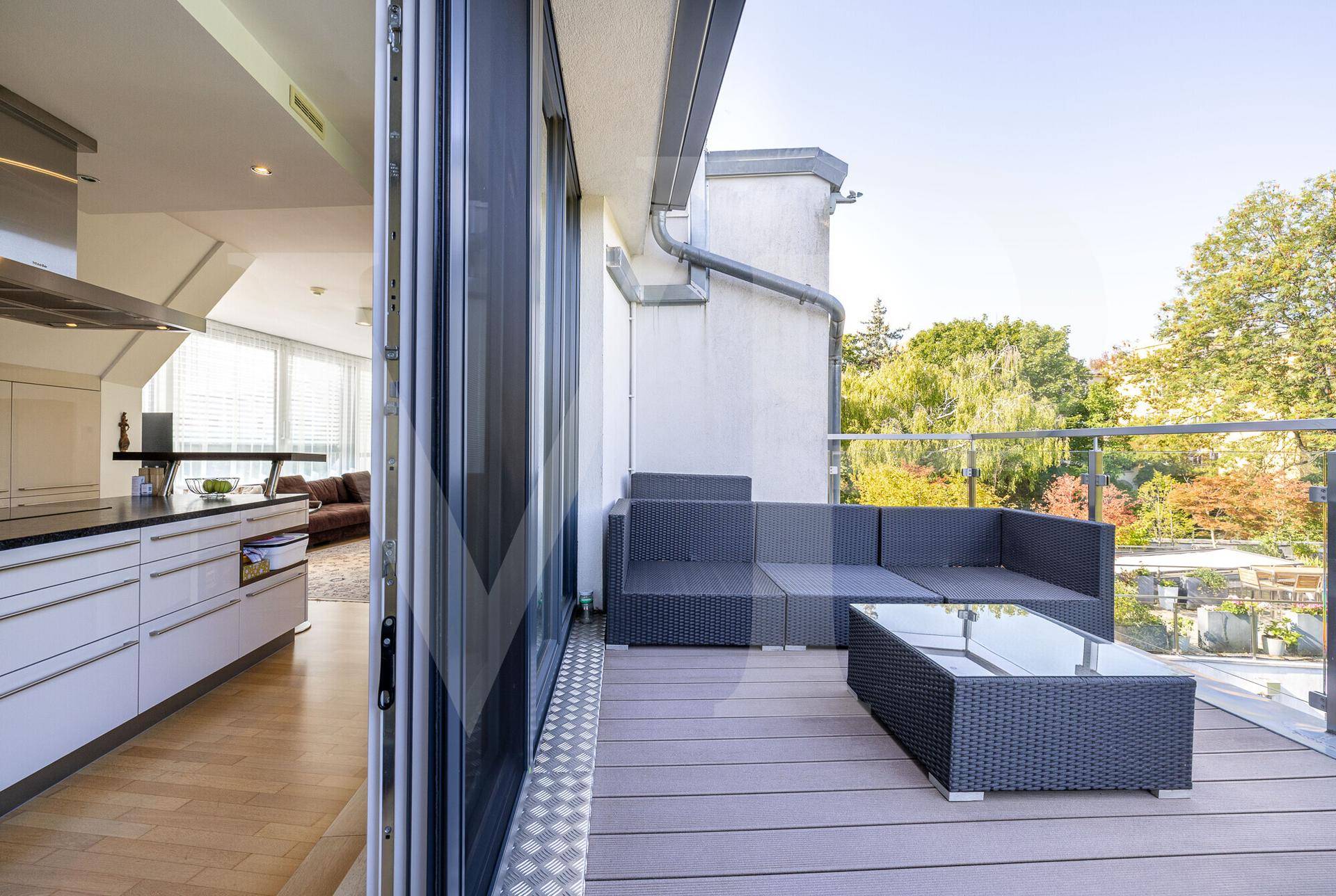 Moderne Küche mit Kochinsel und direktem Zugang zu einer möblierten Terrasse mit Sitzgelegenheiten.