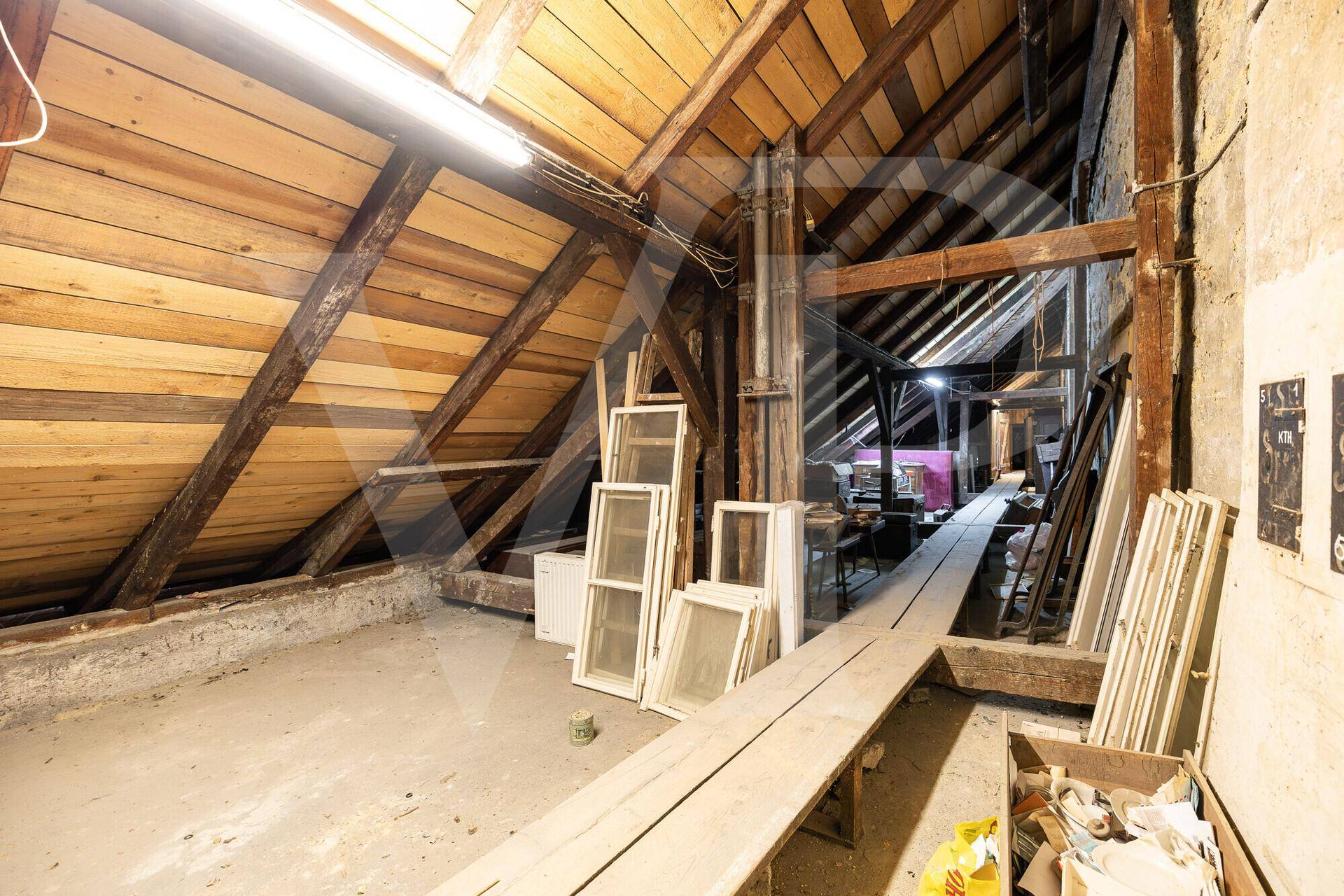 Unausgebauter Dachboden mit sichtbaren Holzbalken und schrägen Wänden, bereit für den Ausbau.