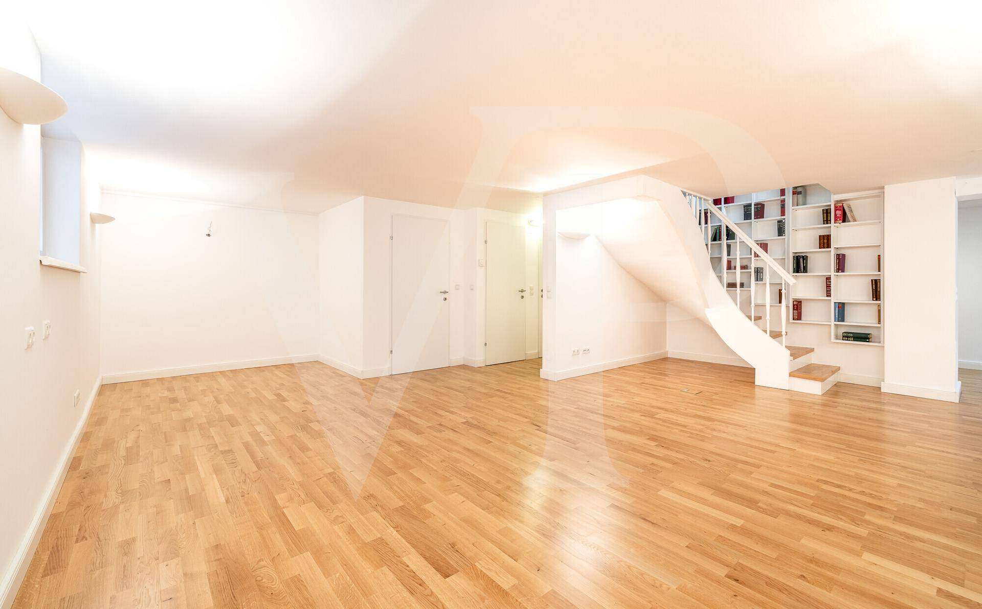Geräumiger, leerer Kellerraum mit Holzboden und weißen Wänden, vielseitig nutzbar.