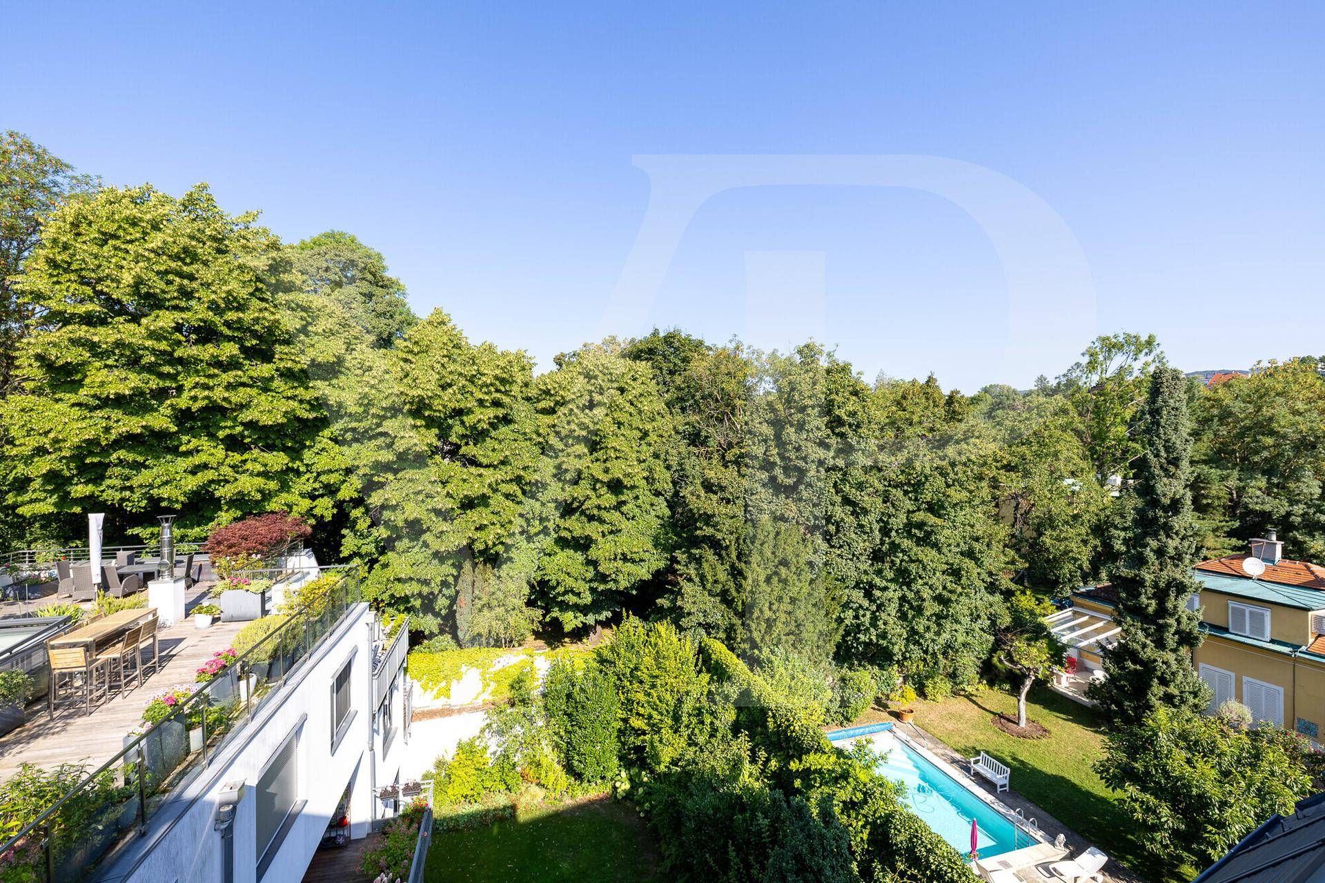 Weitläufige grüne Umgebung mit Bäumen und einem Pool, gesehen aus der Vogelperspektive.