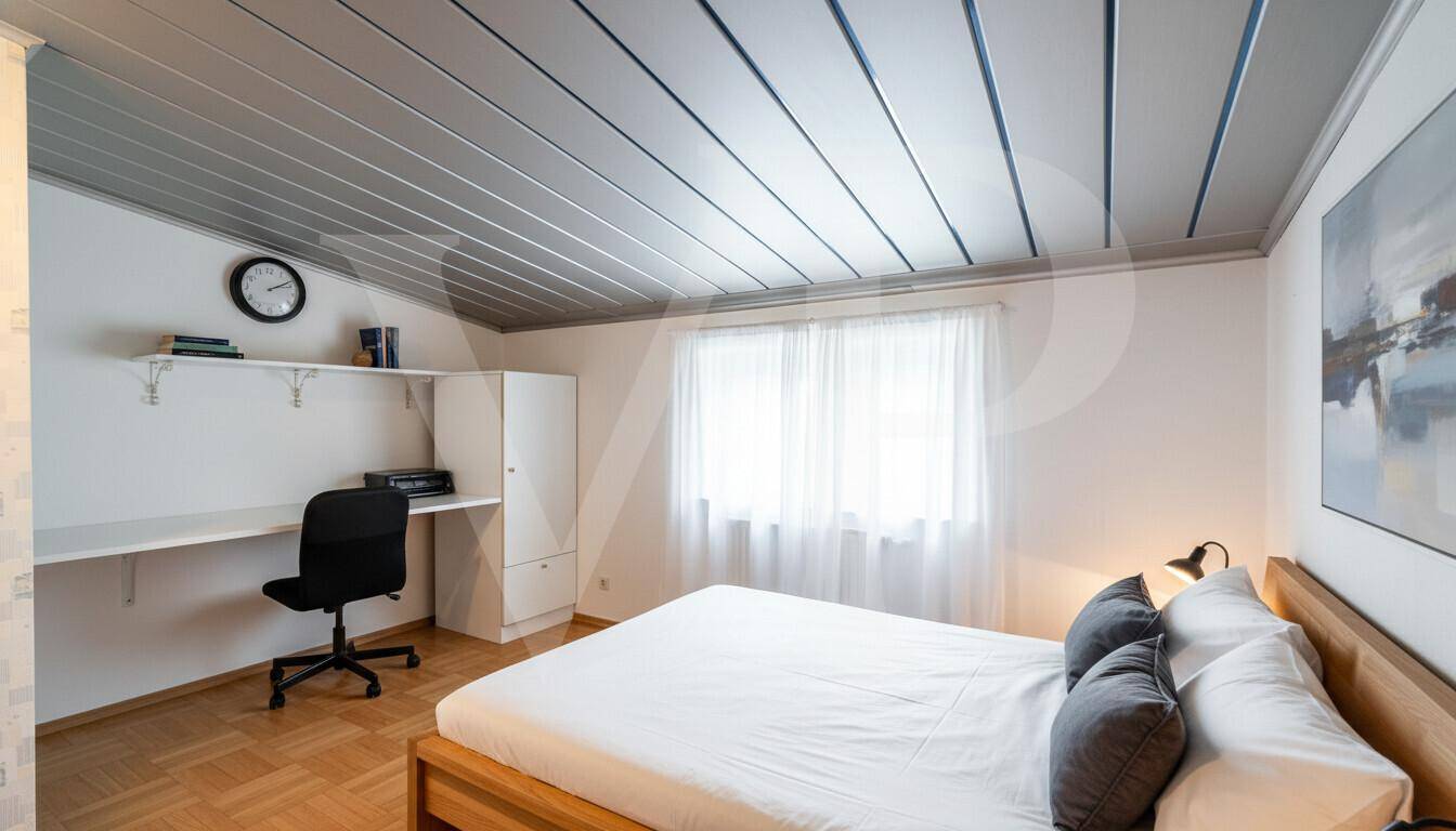 Helles Schlafzimmer mit Holzbett, Schreibtisch und Parkettboden.