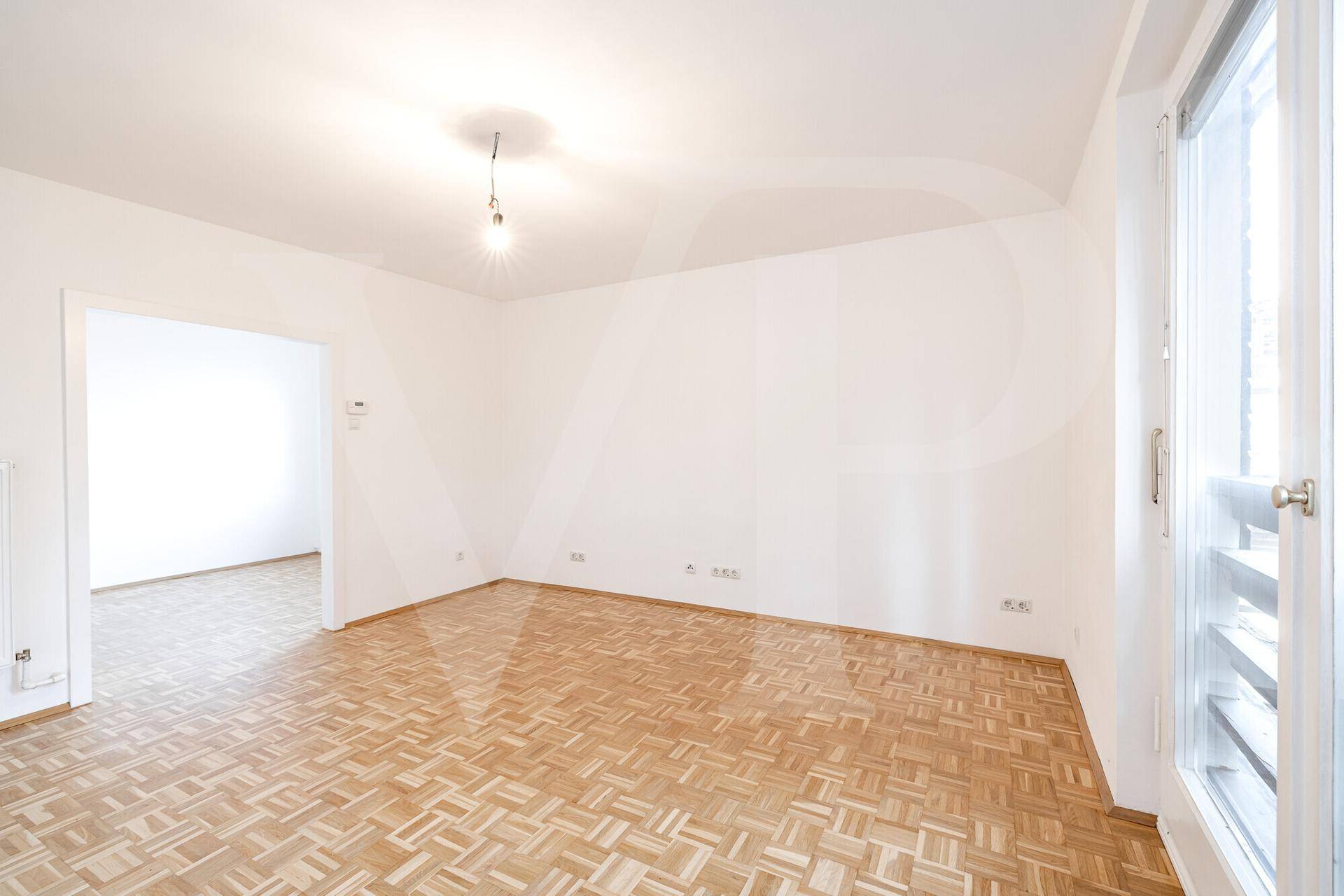 Lichtdurchfluteter Wohnbereich mit Parkettboden und Zugang zu einem Außenbereich.