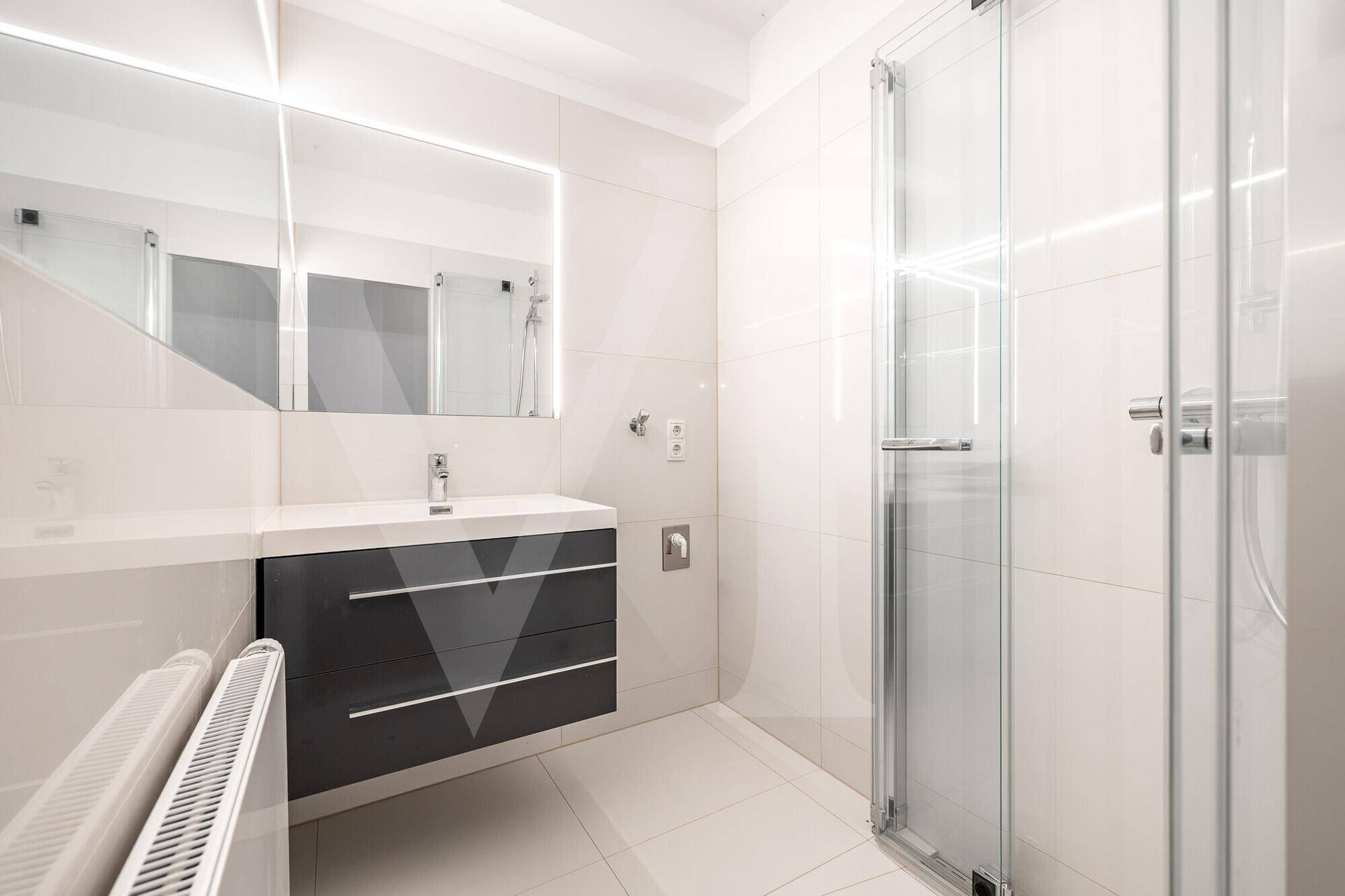 Modernes Badezimmer mit weißen Fliesen, elegantem Waschtisch und einer geräumigen Duschkabine.