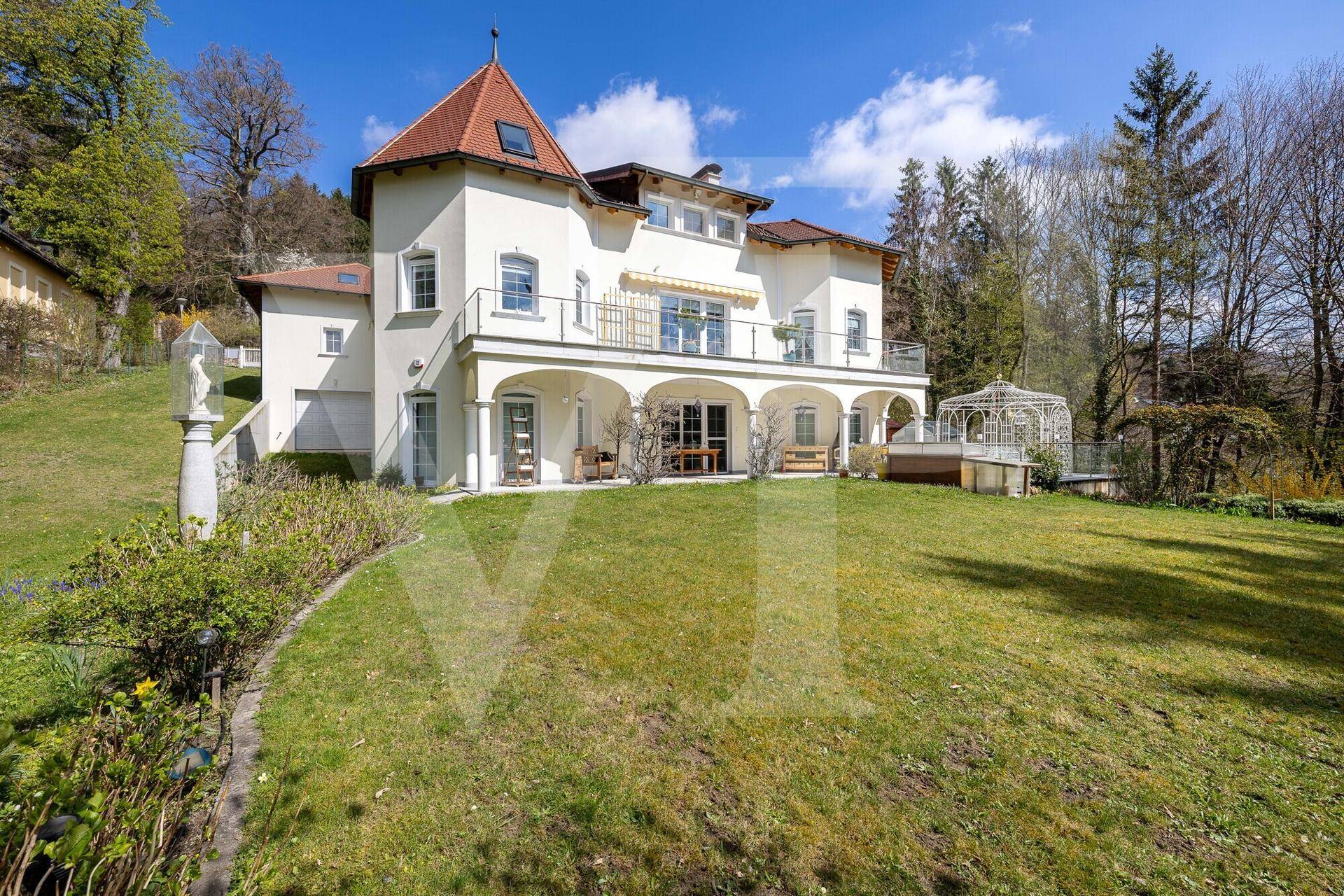 Die elegante Villa mit großem Garten und einem dekorativen Pavillon unter blauem Himmel.