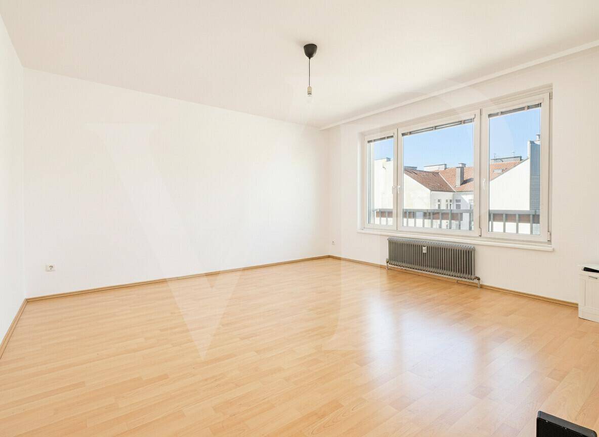 Leeres Zimmer mit hellem Parkettboden und einem Fenster, das für natürliches Licht sorgt.