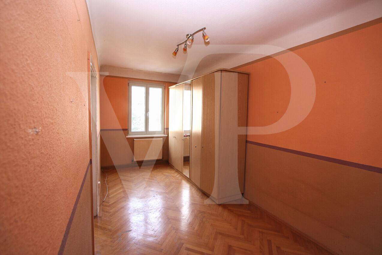 Schlafzimmer mit orangefarbenen Wänden, Parkettboden und einem Kleiderschrank.