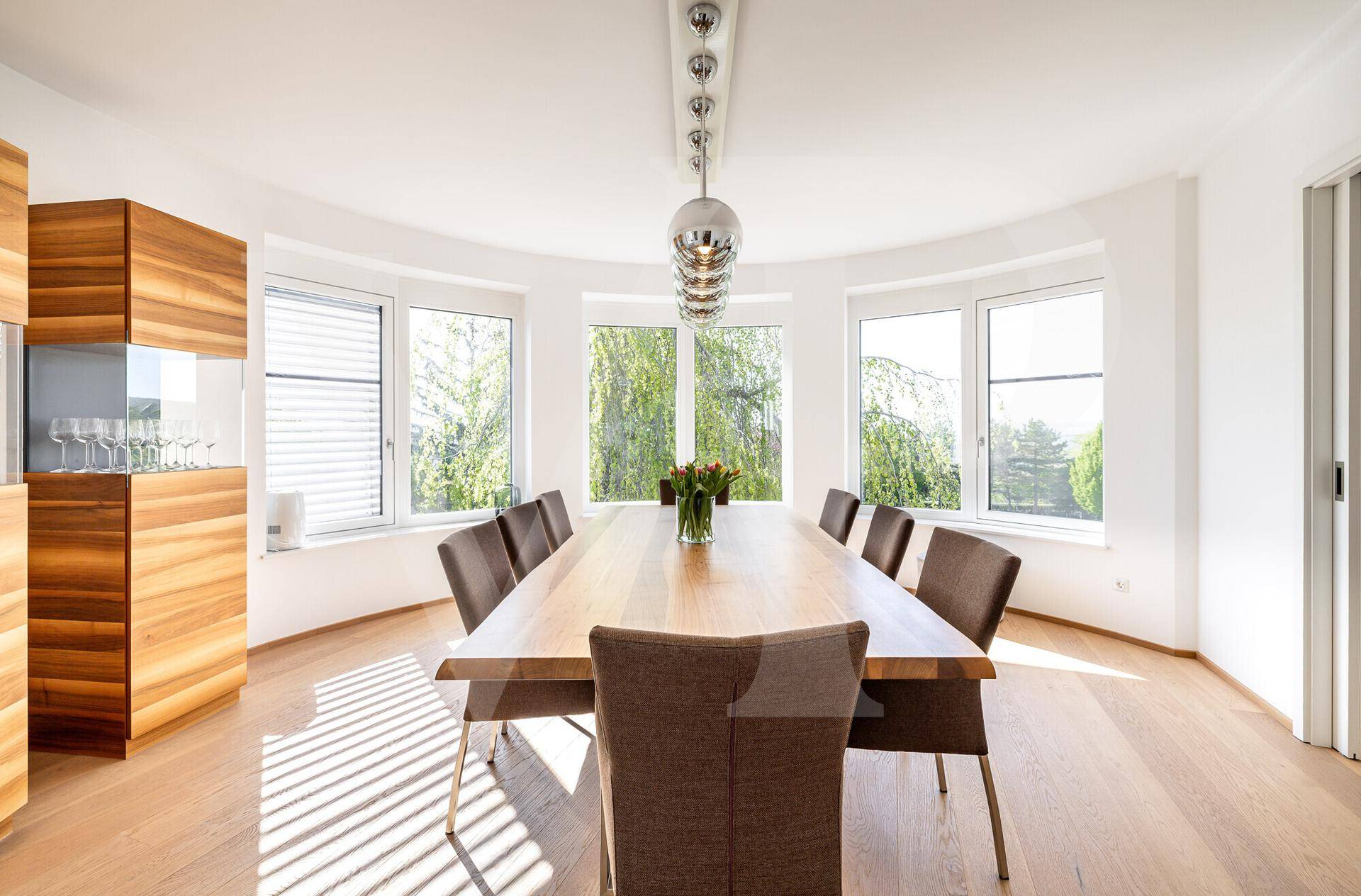 Heller Essbereich mit großem Holztisch, modernen Stühlen und weitem Blick in den Garten.
