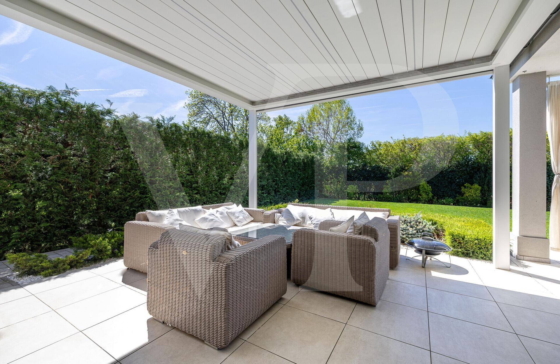 Überdachte Terrasse mit bequemen Loungemöbeln und Blick auf den gepflegten Garten.